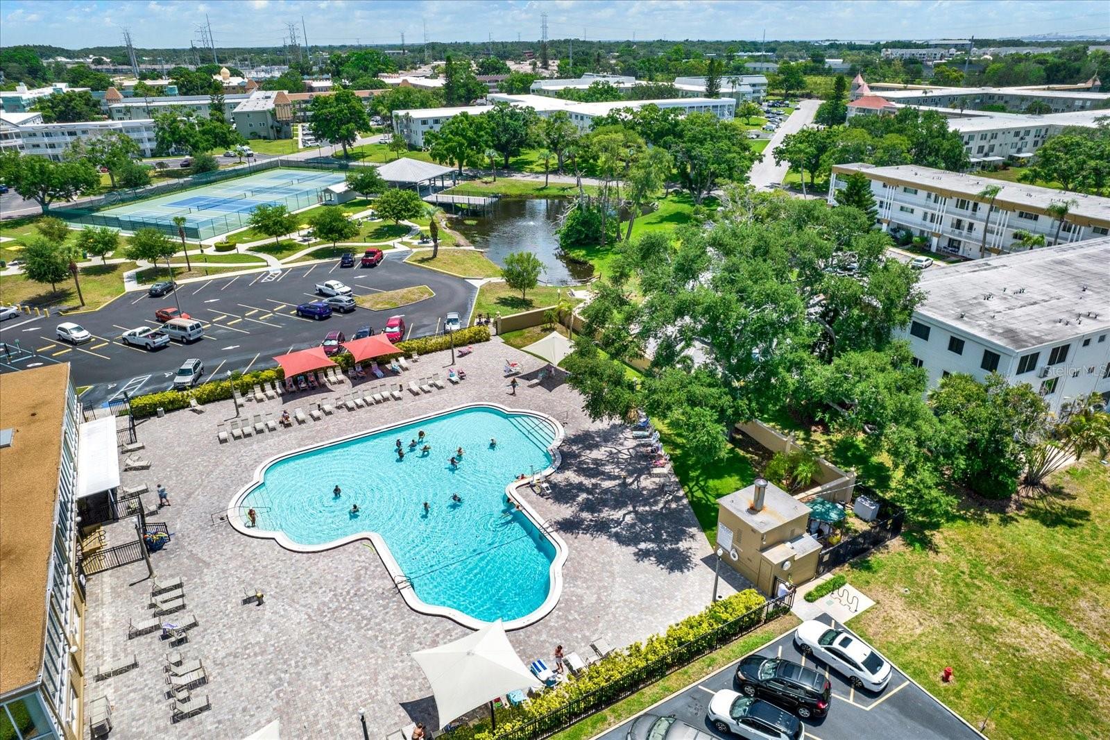 Aerial view of community pool, courts, and pond.