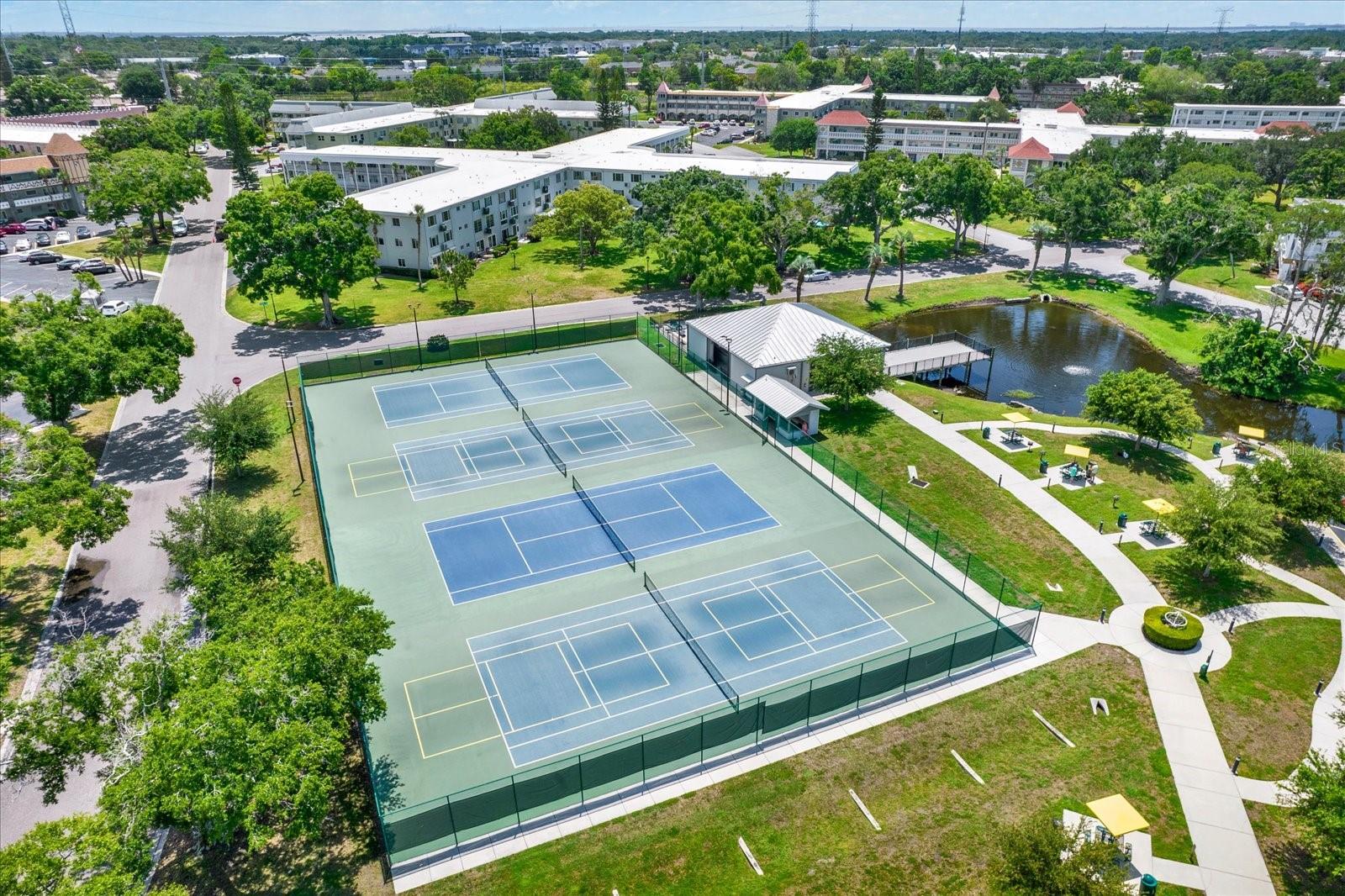 Aerial view of tennis and pickleball courts with pond.