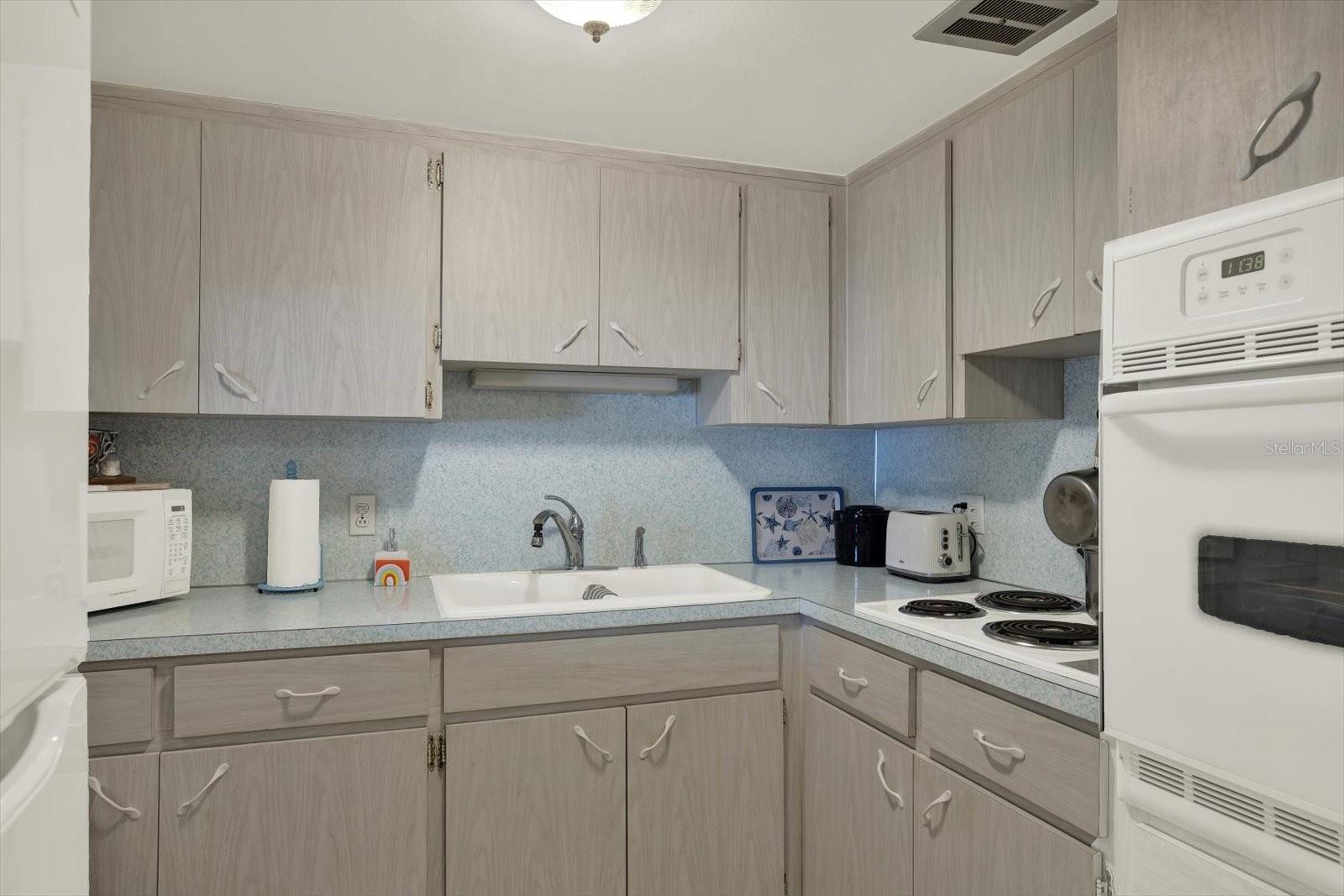 Kitchen with gray cabinetry and white appliances