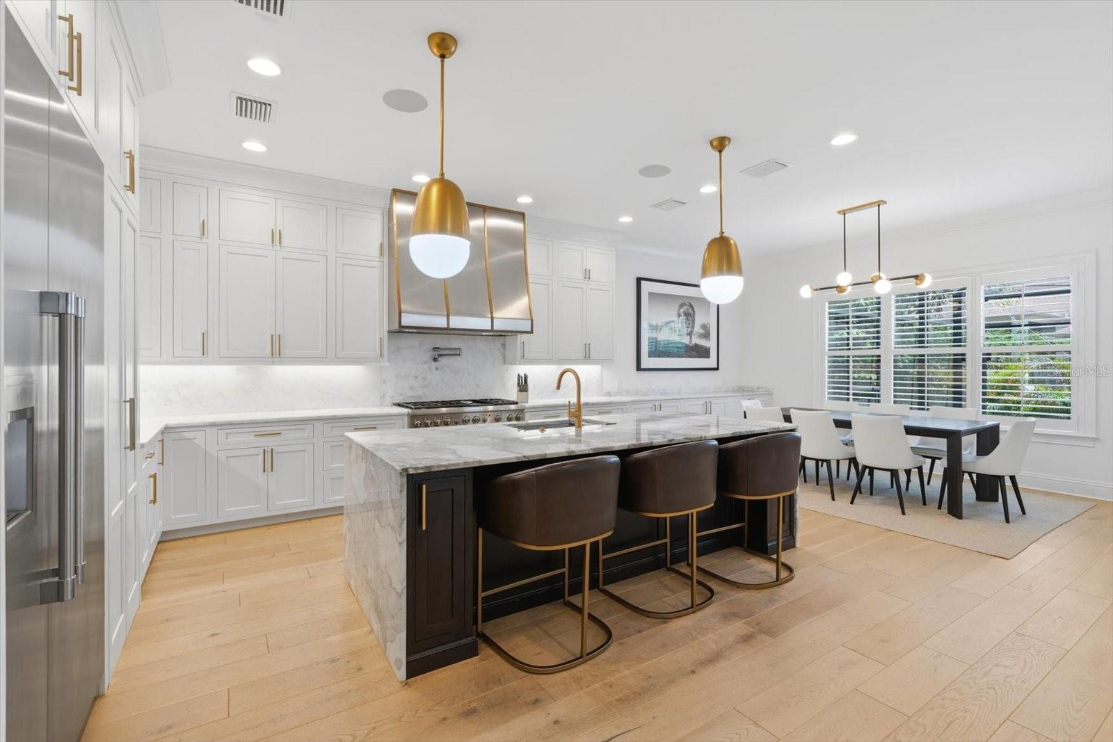chefs kitchen with waterfall marble countertops, hidden pantry with thermador appliances 48' with a separate dining sitting area