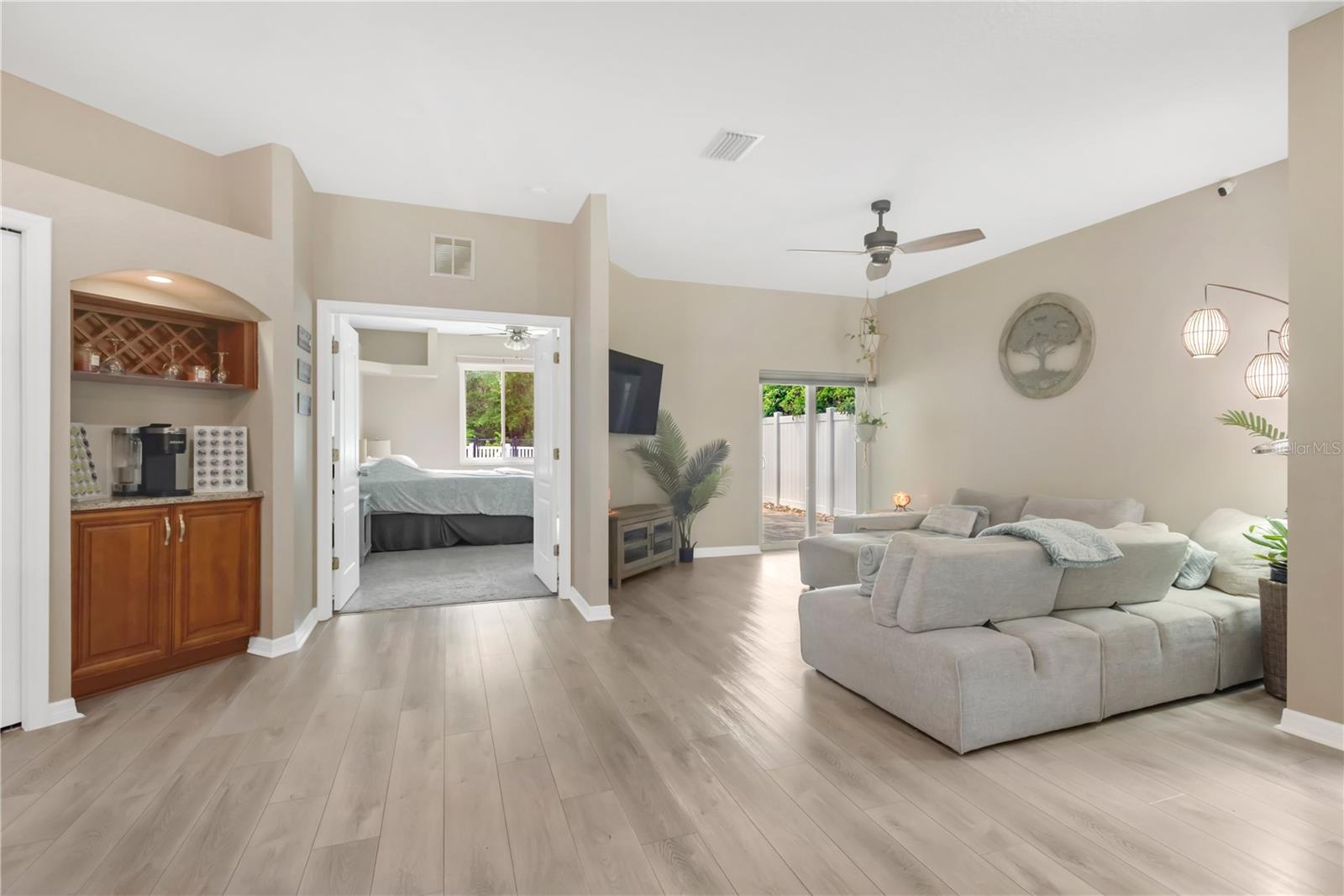 View of Living Room with Sliders out to Back Patio - Bar or Coffee Station and Double Door Entry to Primary Suite