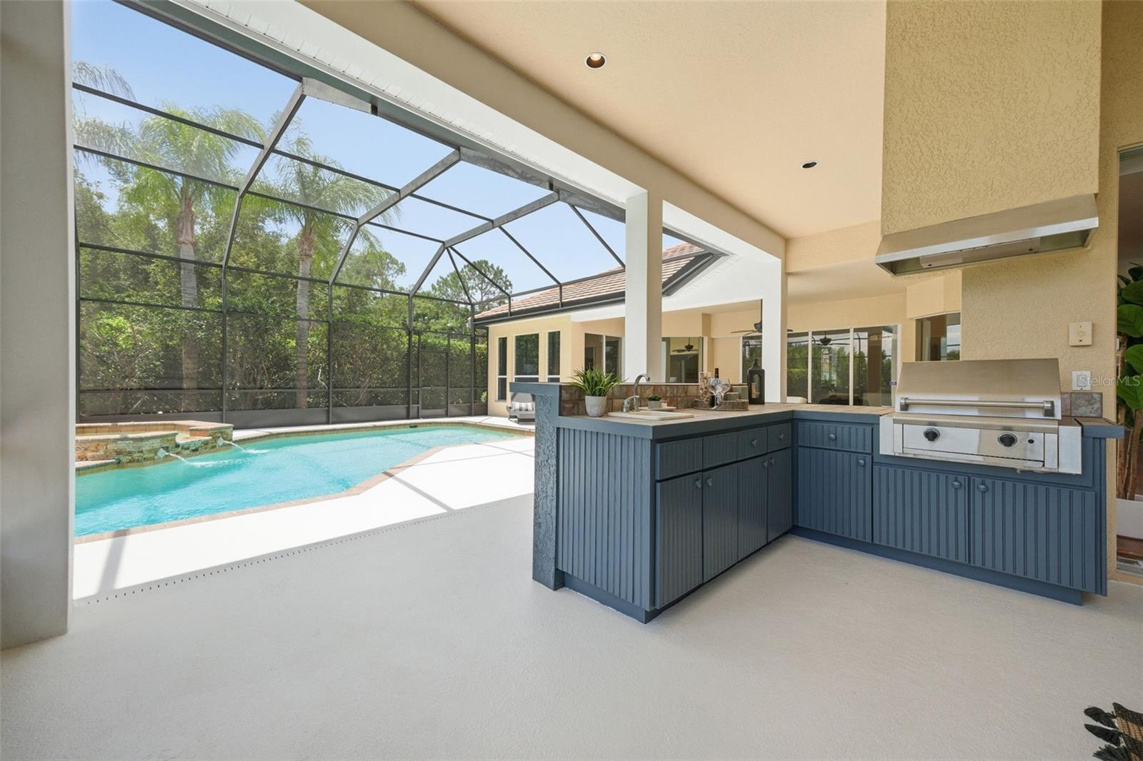 Spacious lanai with outdoor kitchen and pond view