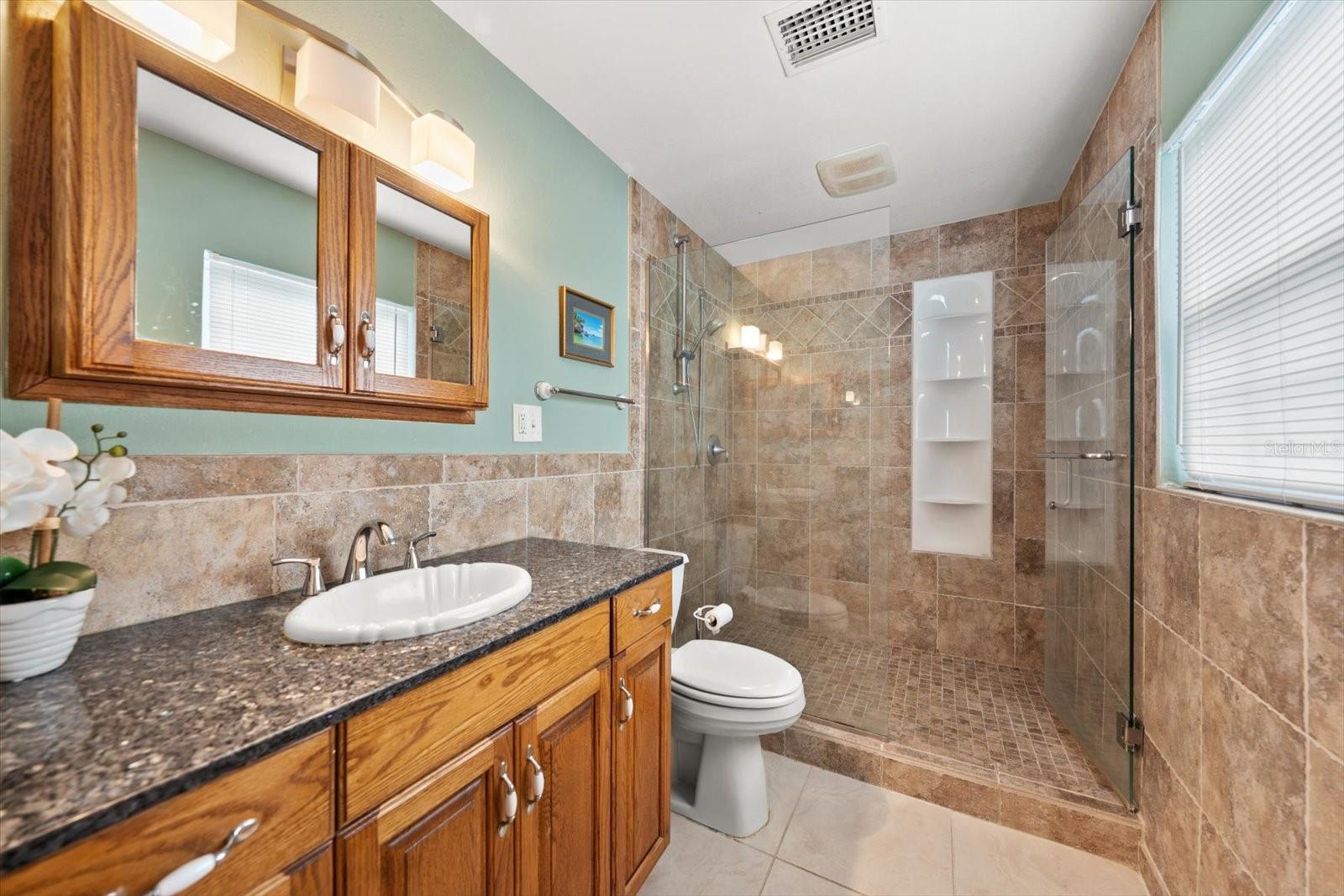 Ensuite bathroom with easily accessible walk-in shower enhanced by attractive glass doors.