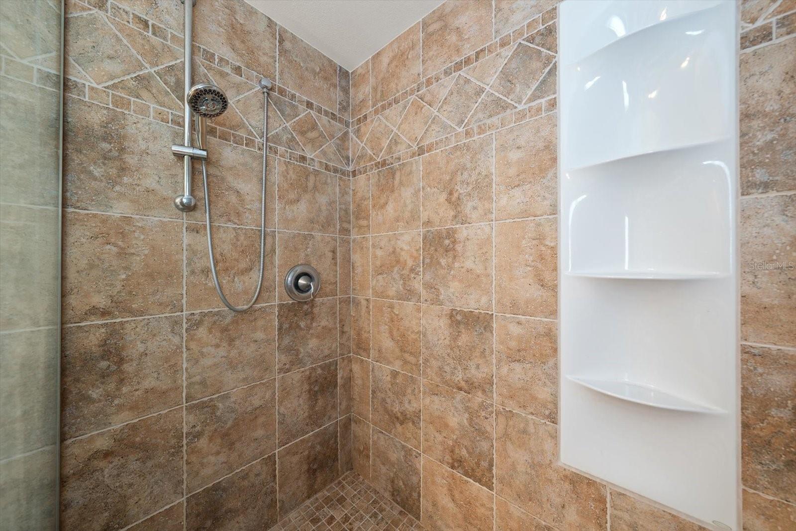 Spacious walk-in shower with built-in shelving.