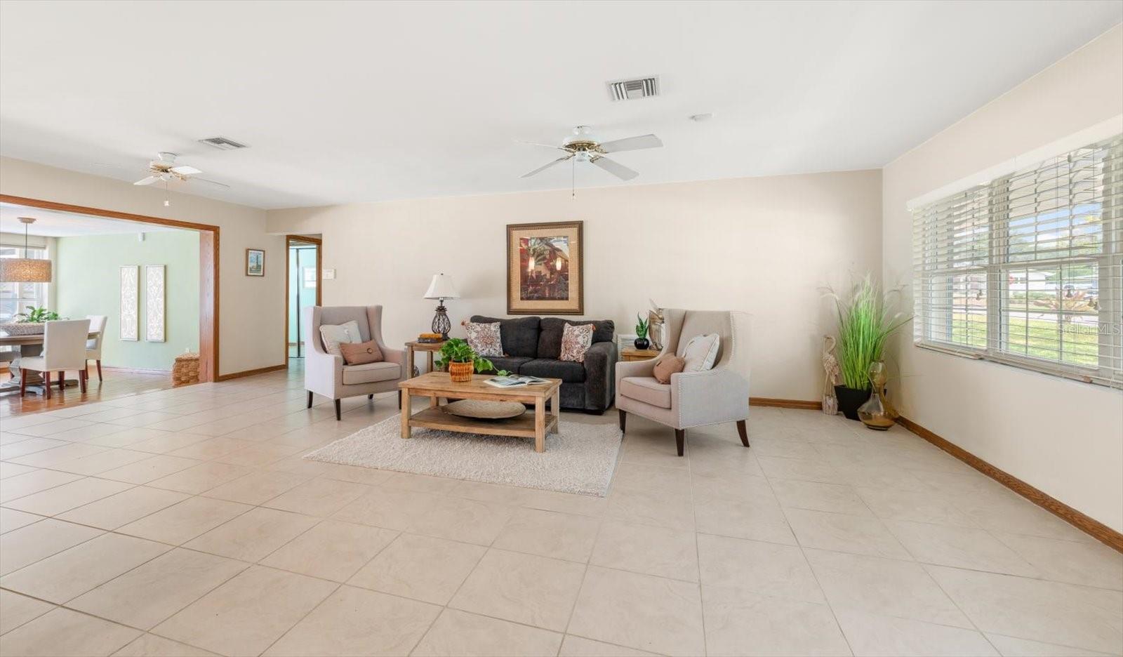 Featuring neutral tiled flooring, crisp white walls, and dual ceiling fans, the room's generous proportions offer the ultimate flexibility for configuring your ideal layout.