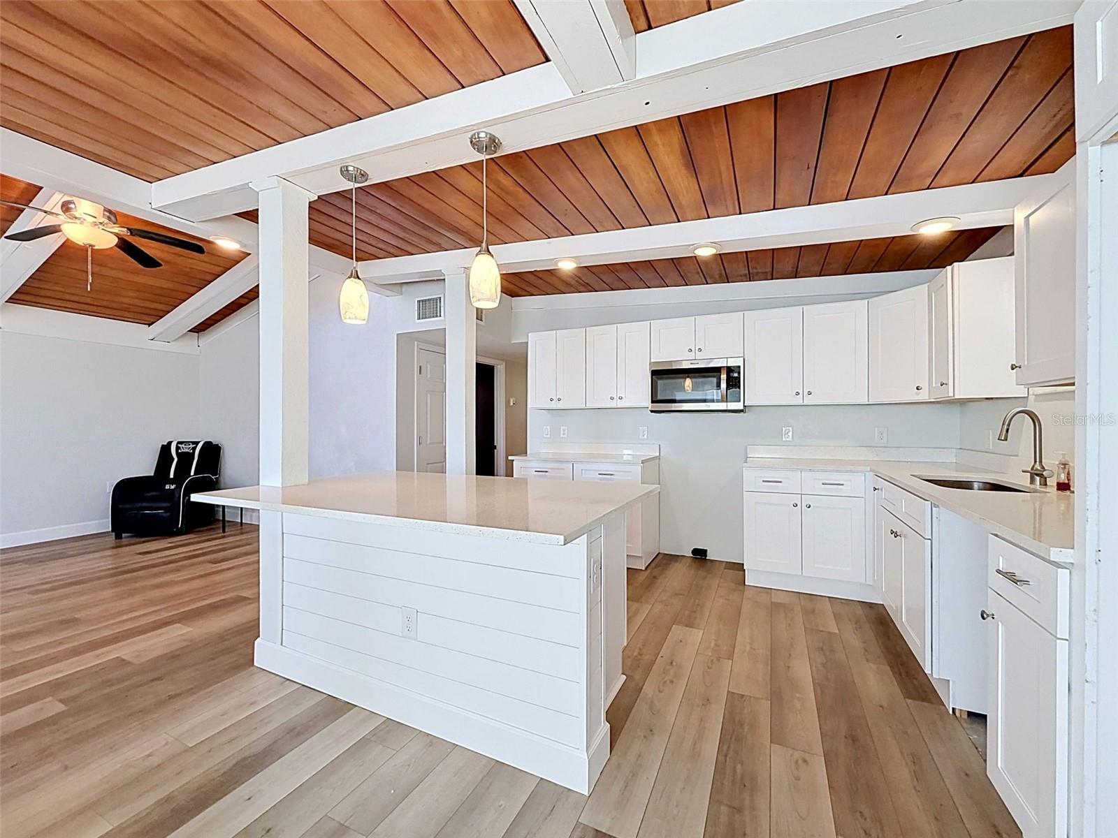 Renovated kitchen featuring quartz countertops, shaker cabinetry, and oversized center island.