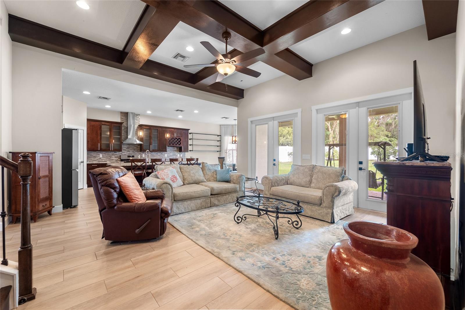 Great room with striking custom wood-beam ceiling, open to the kitchen and sliding doors to the covered patio