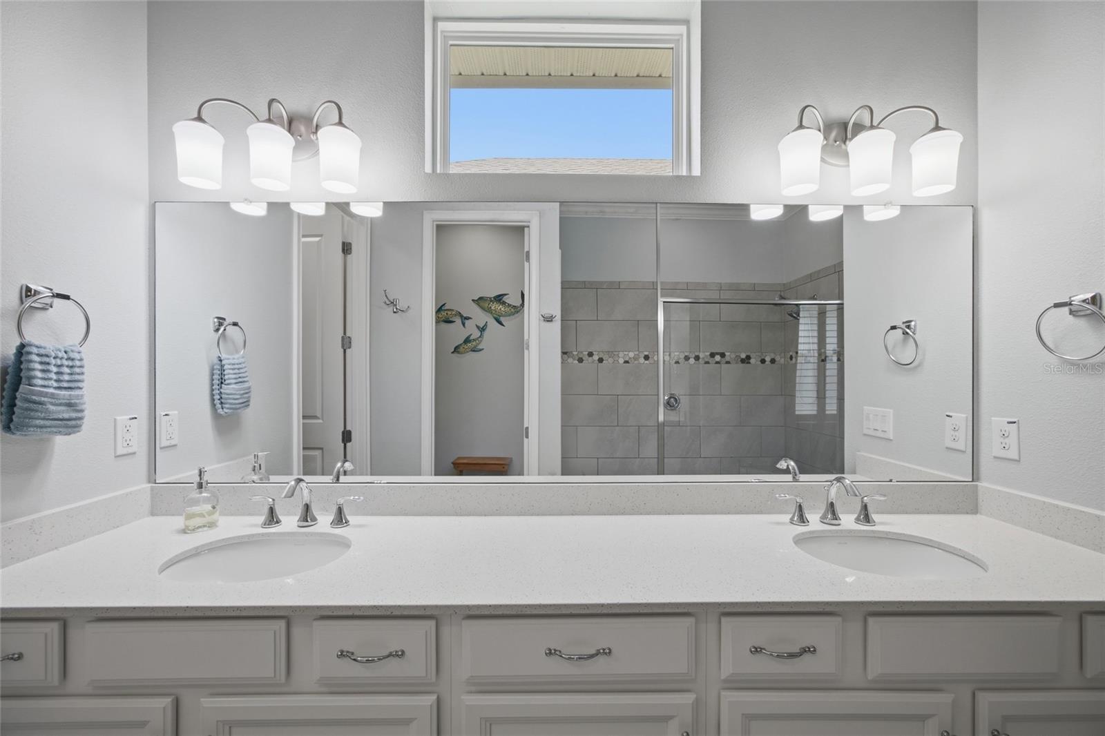 Primary bathroom with quartz counters, dual sinks and window to bring in natural light.