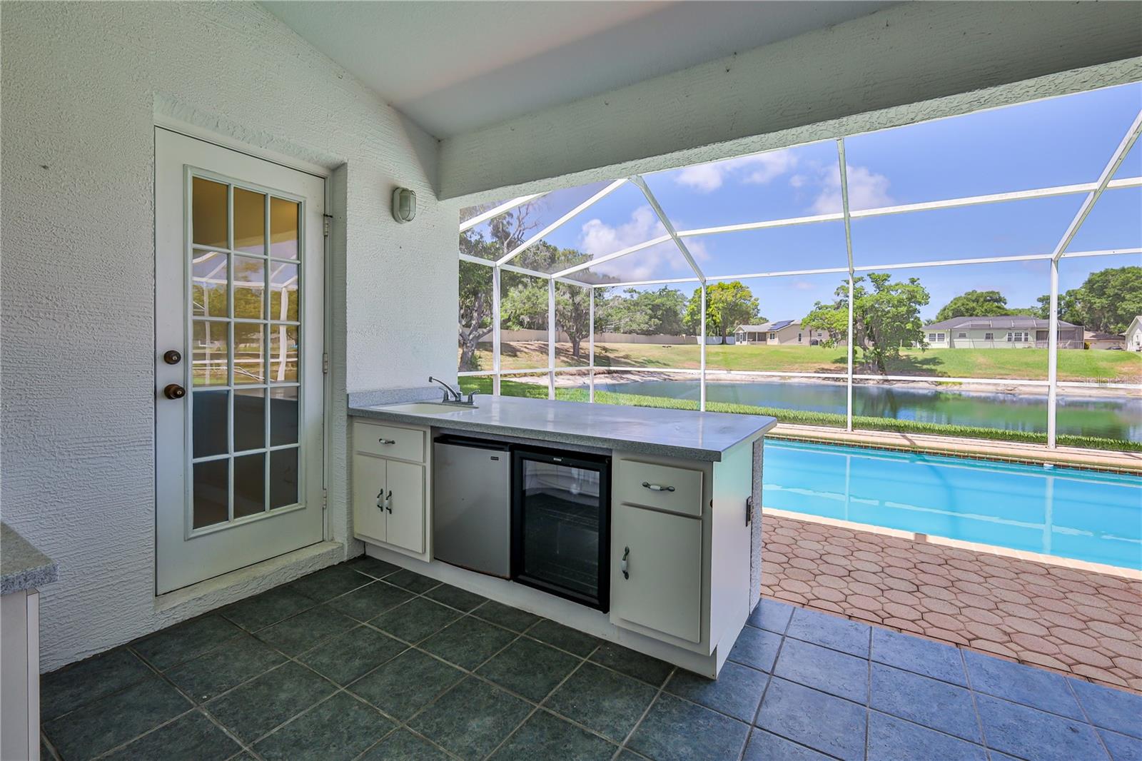 Ceramic tile floor. Outdoor kitchen with corian countertops, wet bar, fridge and wine cooler. Outdoor shower poolside. Pool bathroom access.