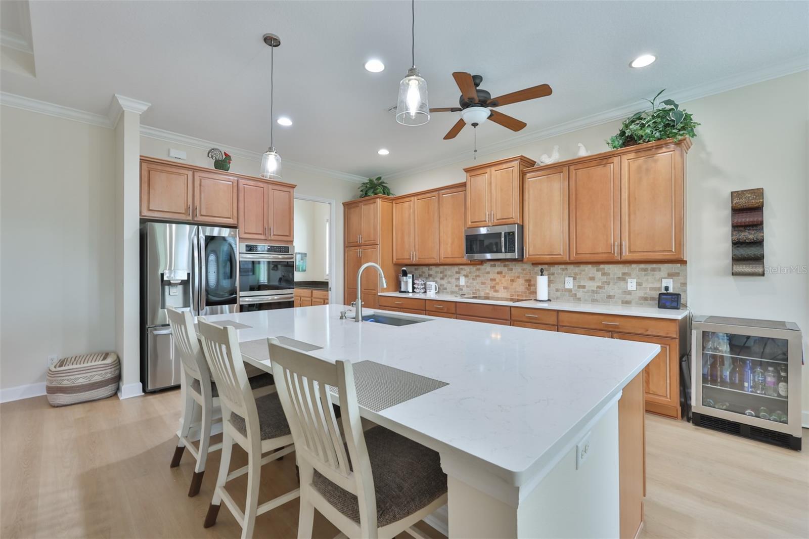 Large breakfast bar compliments the kitchen and modern touches like newer appliances, double stack wall ovens, cooktop, recessed lights and mosaic backsplash.