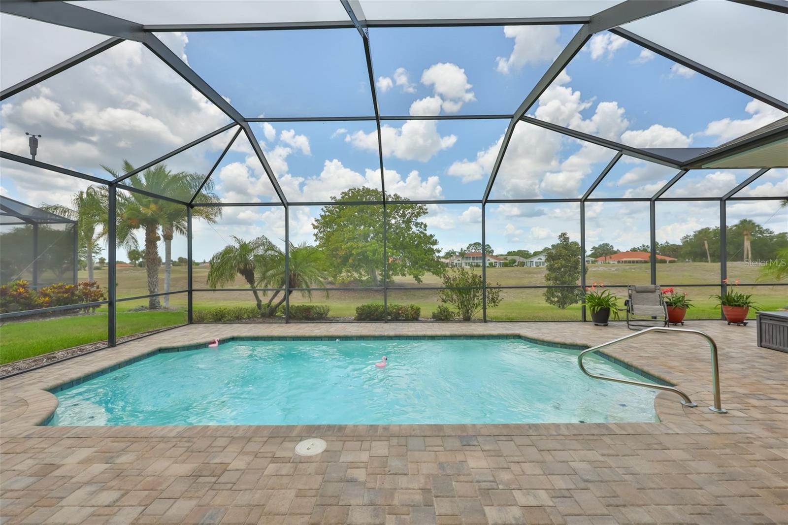 Crystal clear and sparkling pebble tech lined pool overlooking a greenbelt and wide open space.