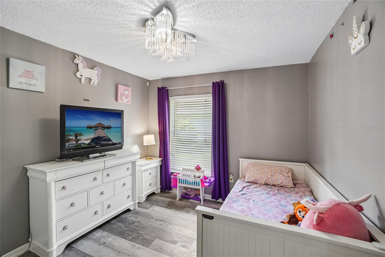 Secondary bedroom with luxury vinyl plank flooring, a crystal flush-mount light fixture,