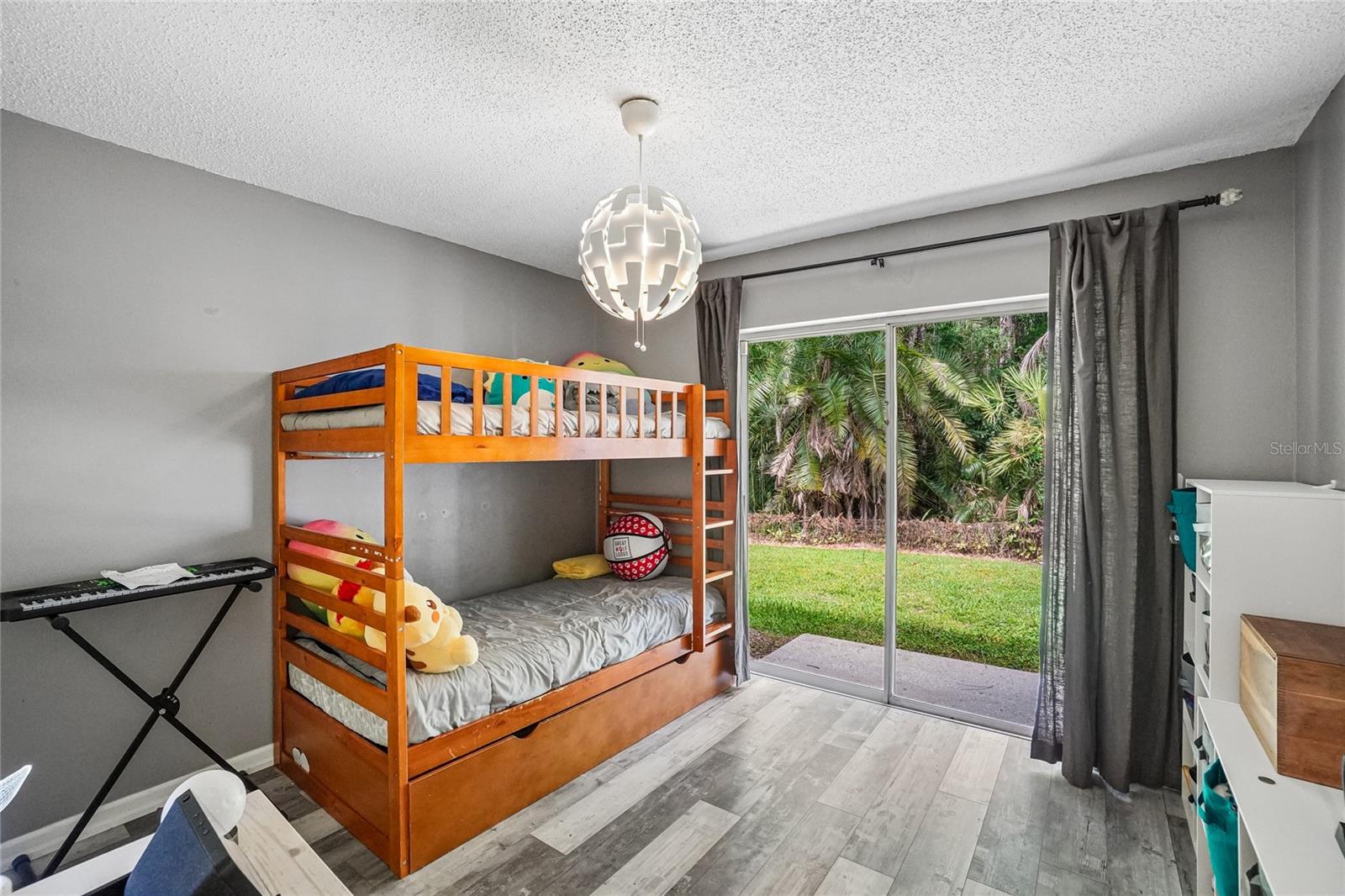 3rd bedroom with luxury vinyl plank flooring, a pendant light fixture, and a sliding glass door with direct backyard access. Conservation views are visible through the glass.