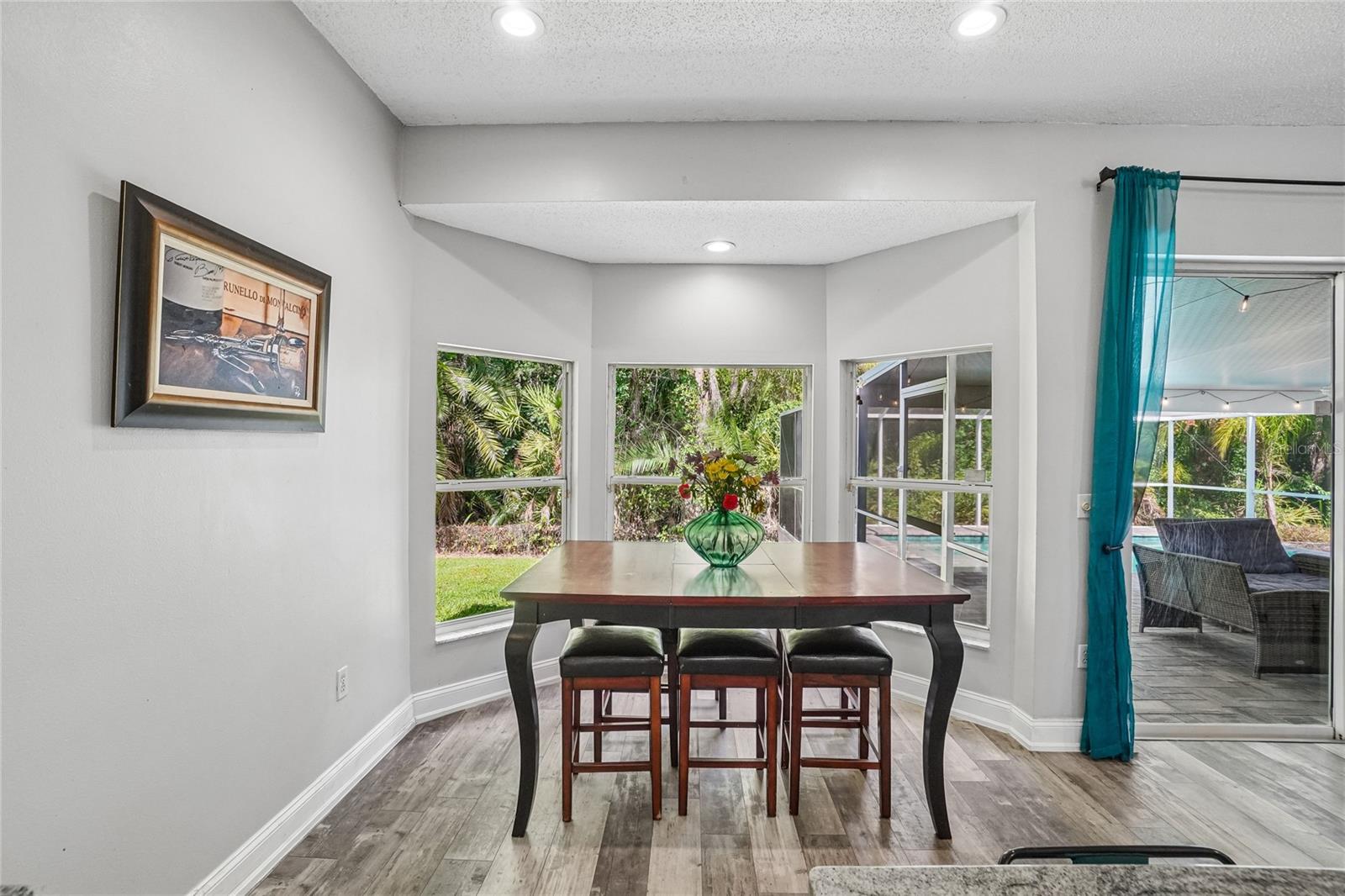 Dining area — Dining area with luxury vinyl plank flooring, recessed lighting. Three windows frame a view of the backyard conservation, with a sliding glass door providing direct access to the screened lanai.