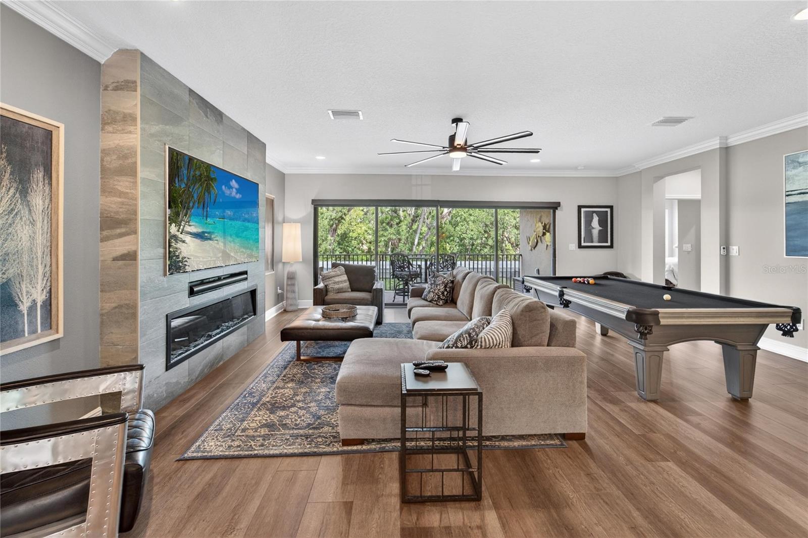 Bonus room view with Luxury flooring, upgraded electric fireplace wall with a built in niche for your tv. A great room for leisure, playing pool and enjoying the gorgeous view from the second story patio.