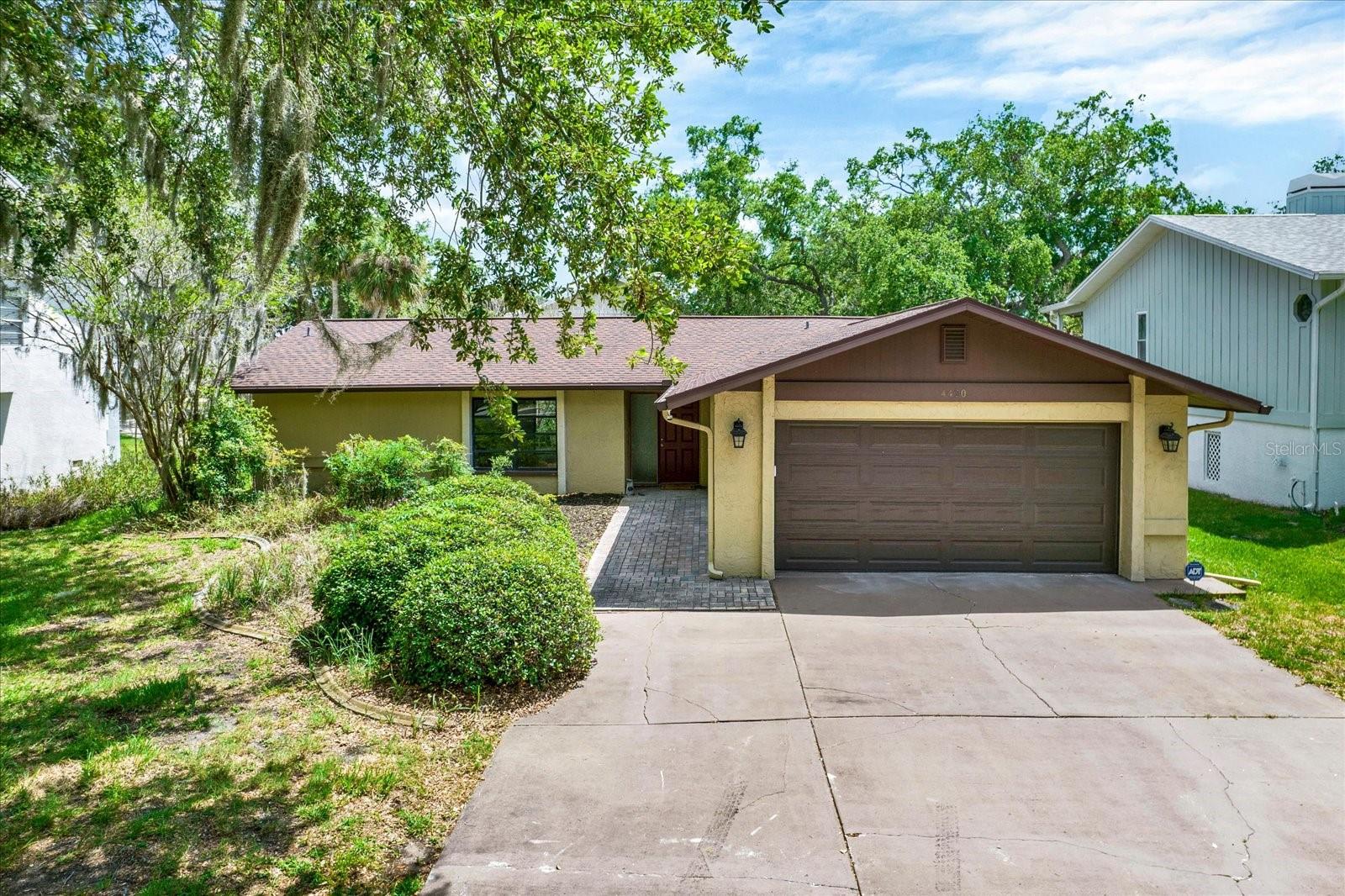 Charming ranch style home featuring a paved front walkway, mature landscaping and an attached 2 car garage.