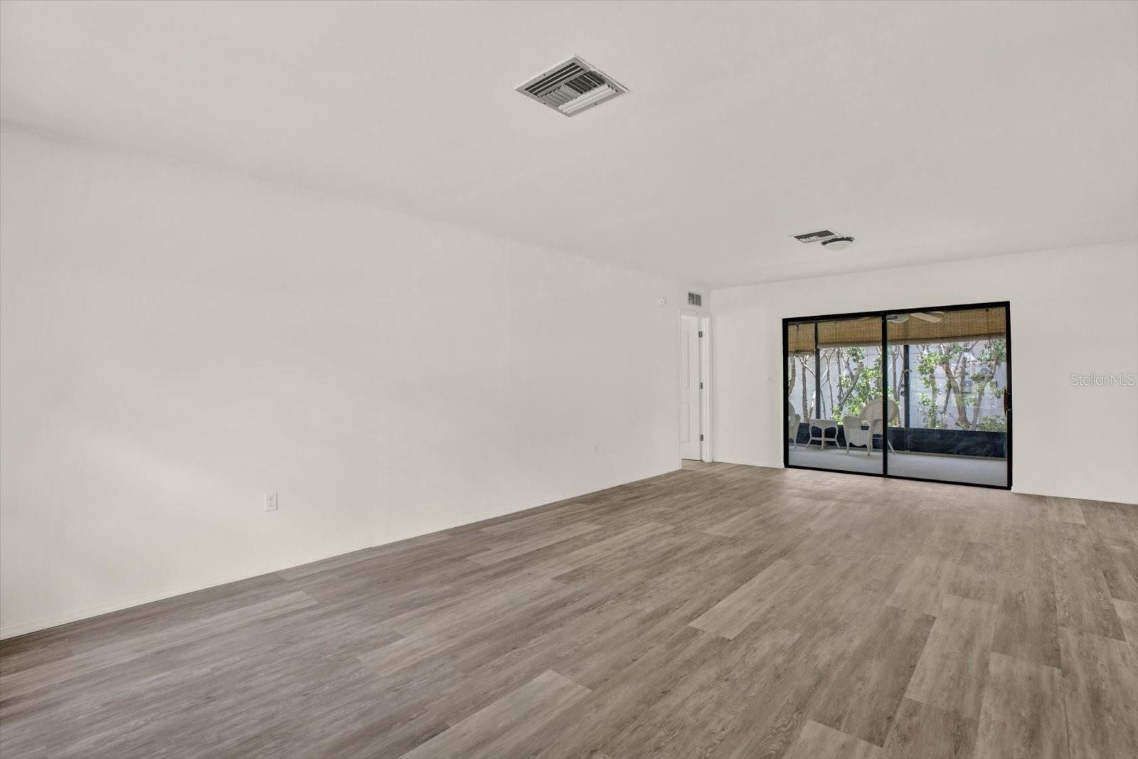 Living area showing the primary suite entry and large sliders leading out to the lanai.