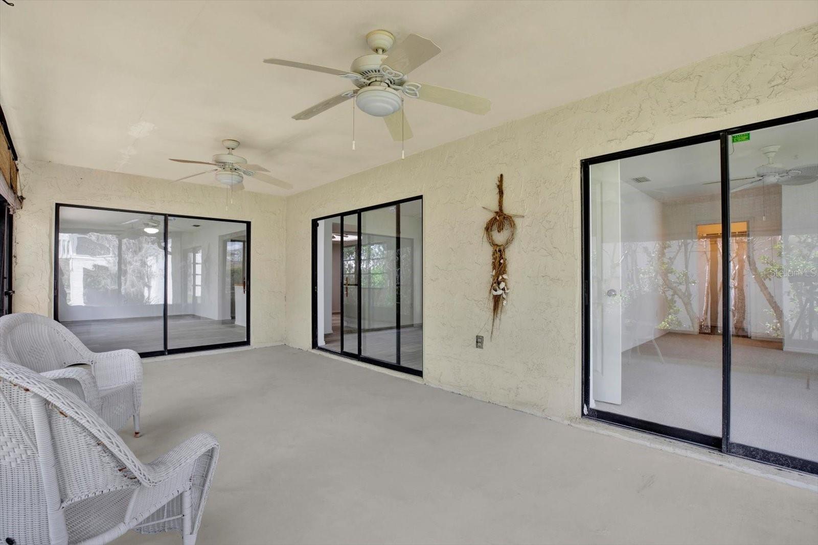 Another view of the massive screened lanai showcasing the multiple sets of sliding glass doors that seamlessly connect the indoor and outdoor living spaces.