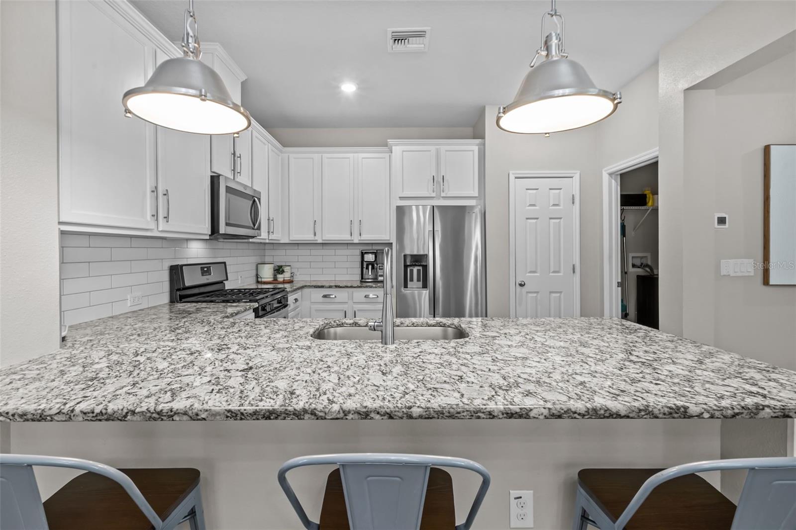 Beautiful kitchen features white cabinetry, granite countertops, and stainless steel appliances