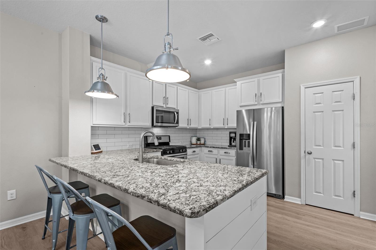 Beautiful kitchen features white cabinetry, granite countertops, and stainless steel appliances