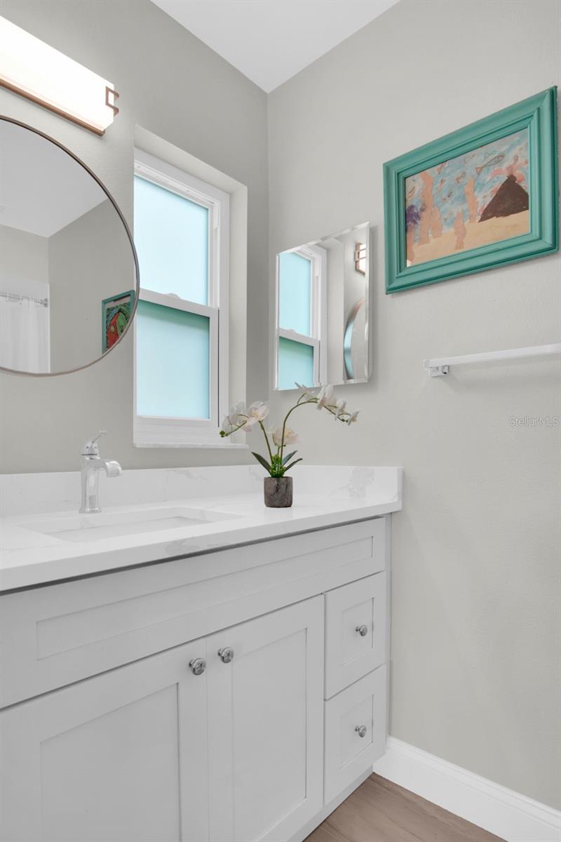 En-suite bath with newer vanity, stone counters, and updated lighting~