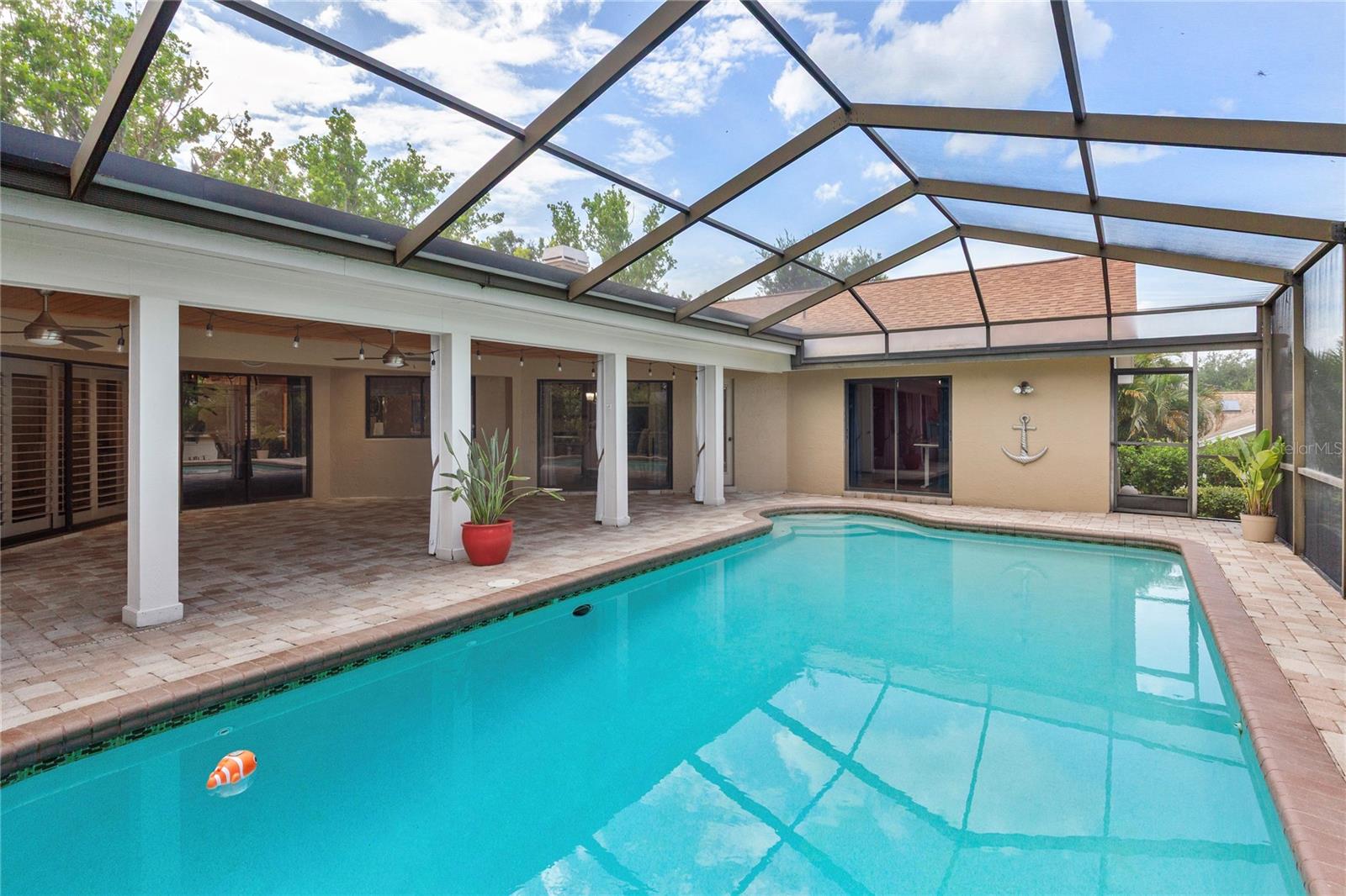 Expansive pool area, where a large screened birdcage enclosure and covered lanai with a natural cypress wood ceiling create a private backyard oasis perfect for relaxing or entertaining year-round.