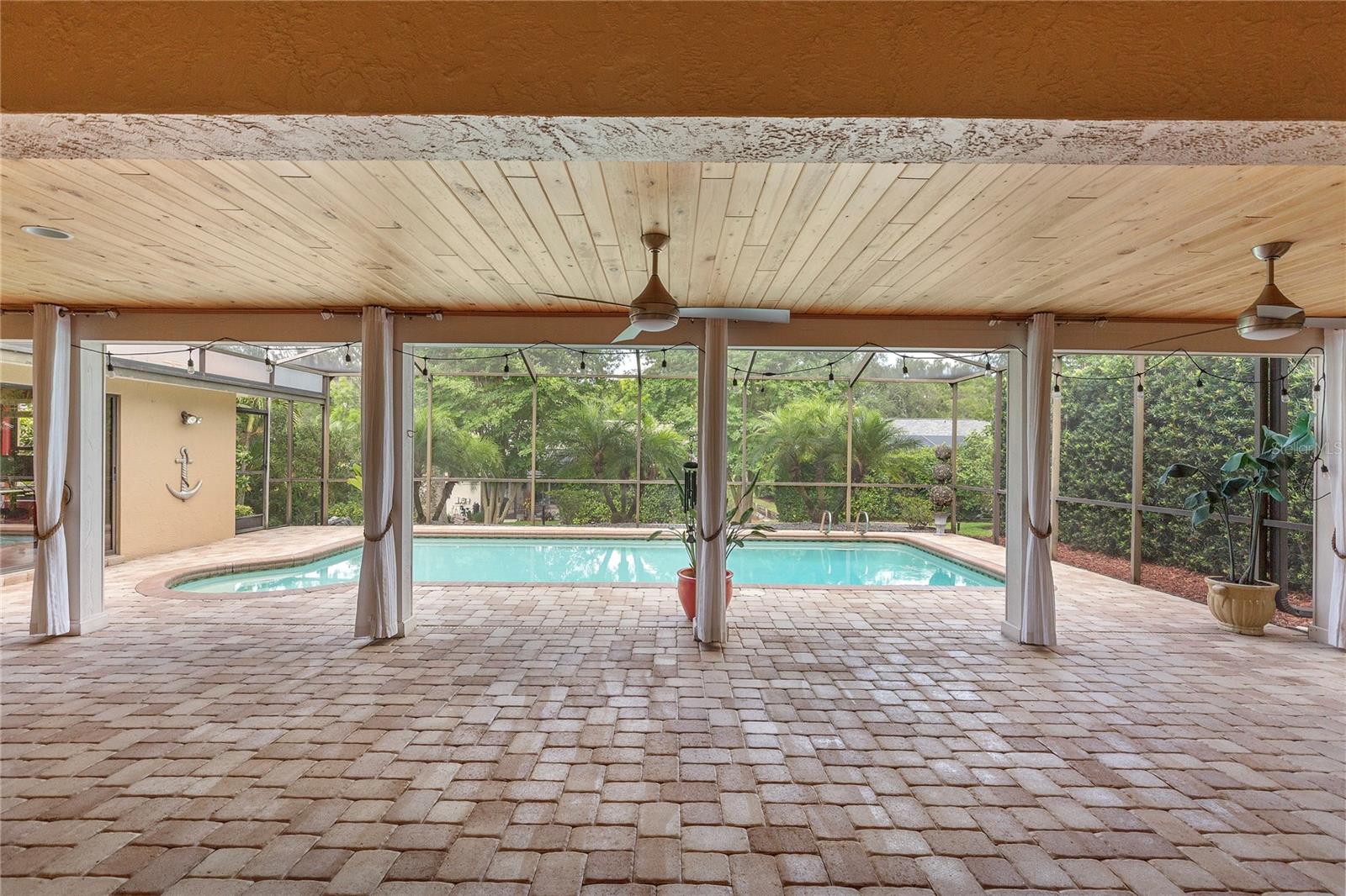 Outdoor living at it's finest! A brick paver walkway welcomes you to the front entrance and continues around the expansive pool area, where a large screened birdcage enclosure and covered lanai with a natural cypress wood ceiling.