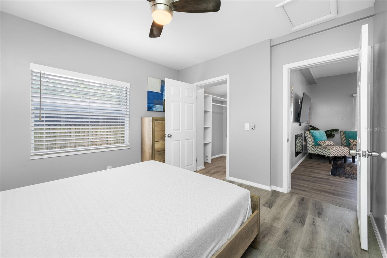 Primary Bedroom suite with walk-in closet, with built in shevles, that opens through to private en-suite updated bathroom with marble tile and glass shower.