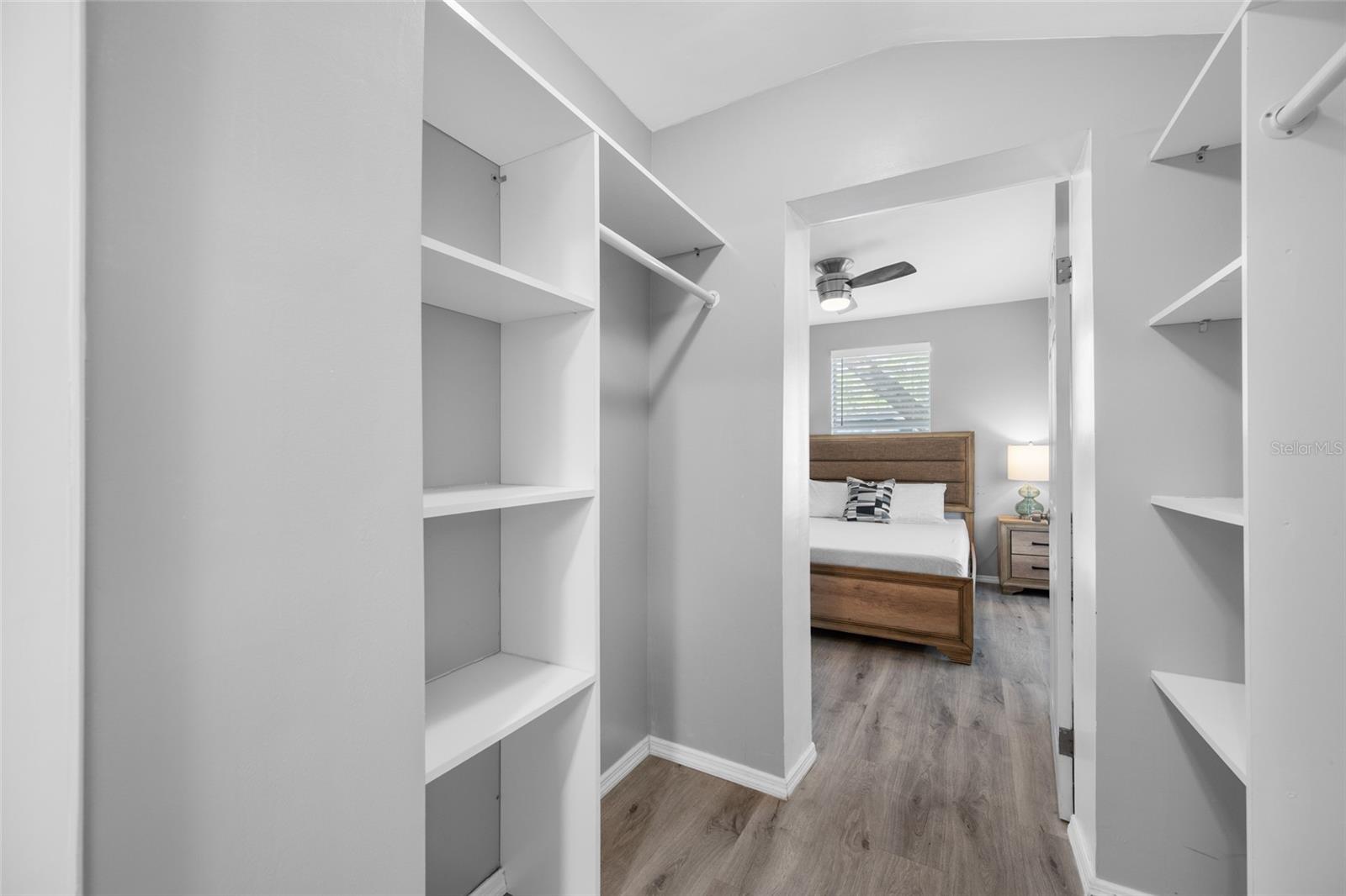 Primary Bedroom suite with walk-in closet, with built in shevles, that opens through to private en-suite updated bathroom with marble tile and glass shower.