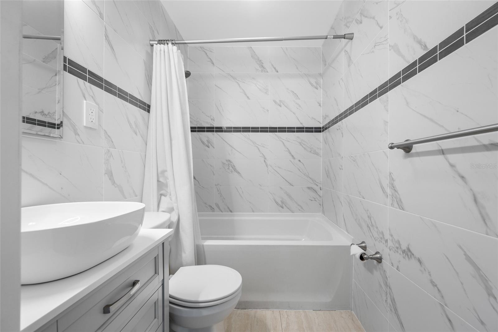 Bathroom 2 features an upgraded vanity, marble tiles, and a bathtub with shower.