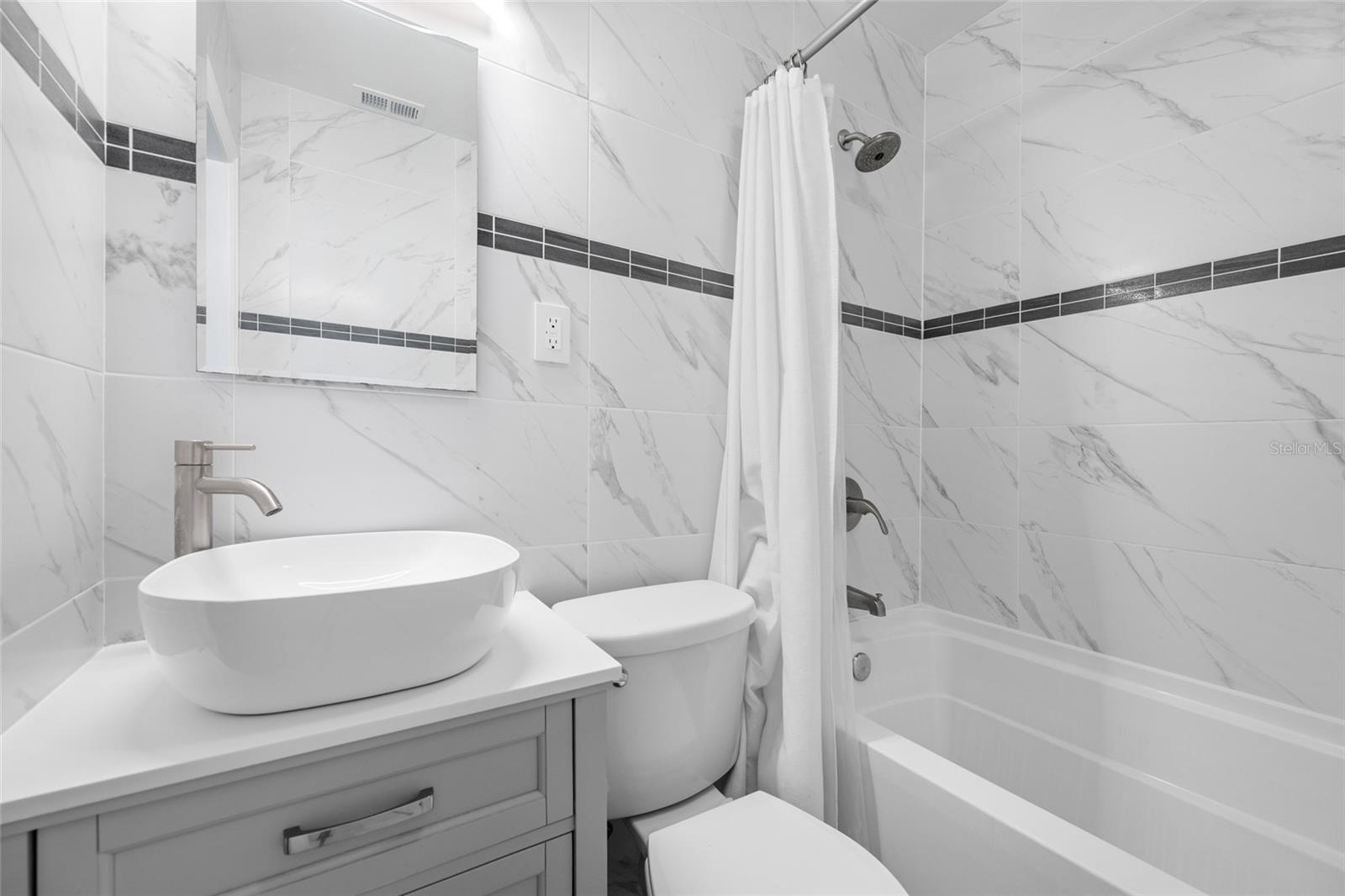 Bathroom 2 features an upgraded vanity, marble tiles, and a bathtub with shower.