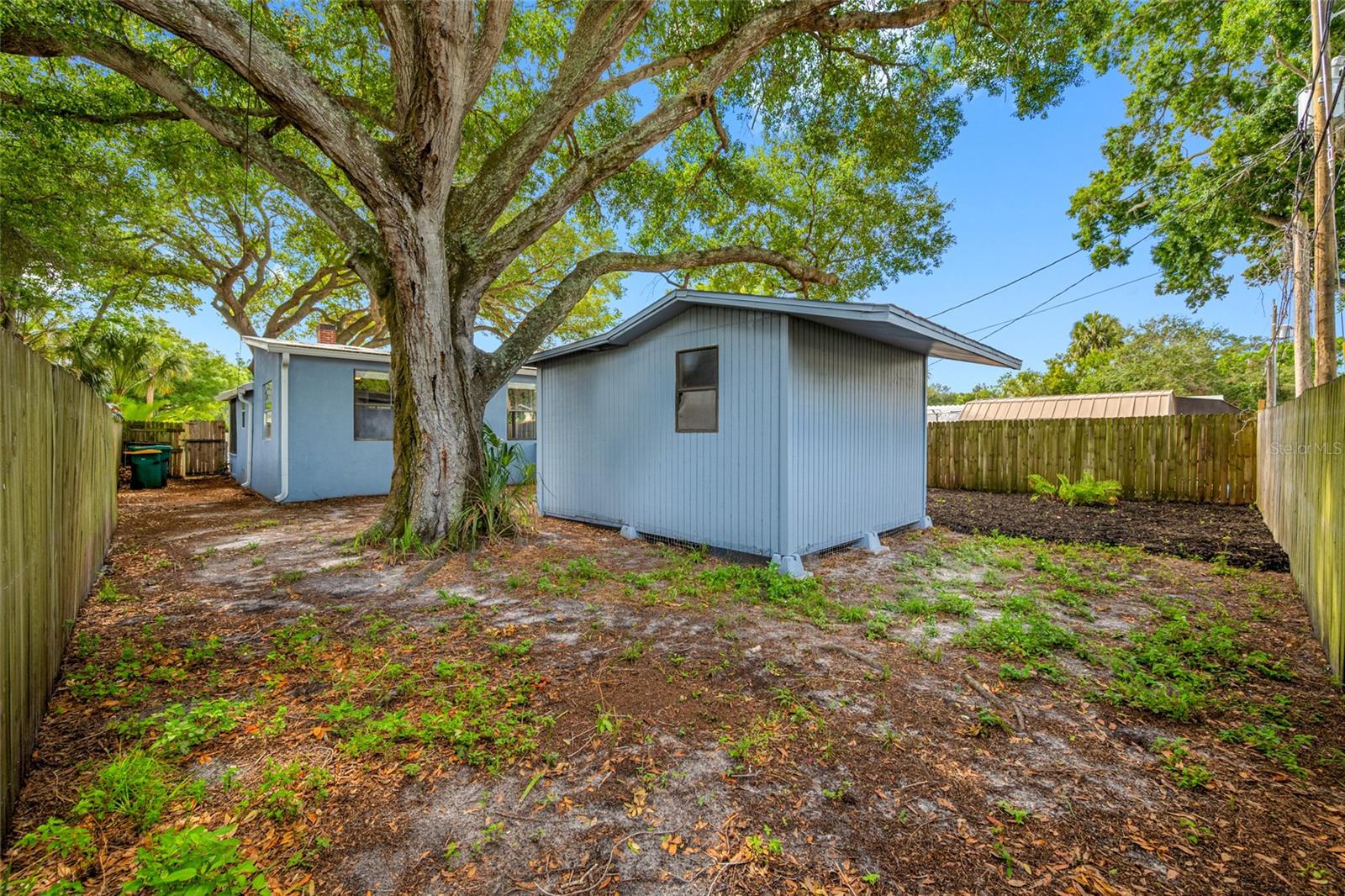 Fenced in back yard with 20ft wide deck that leads to detached workshop and shed.