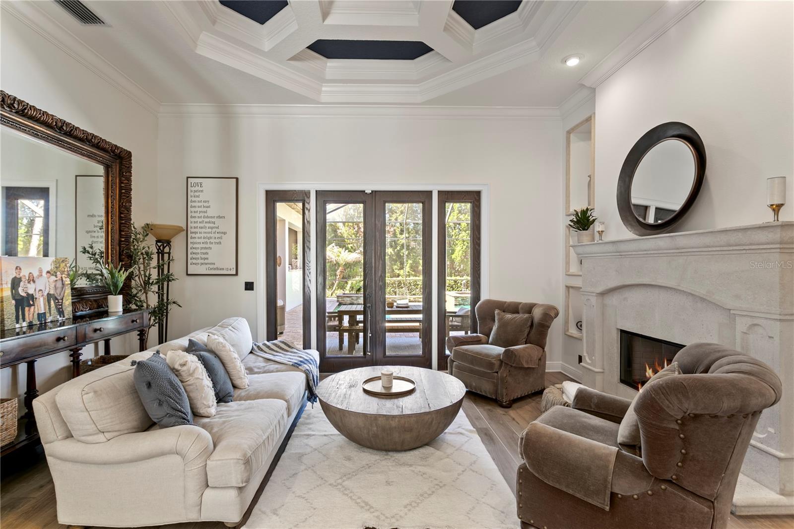 Elegant living space with coffered ceiling and stone fireplace.