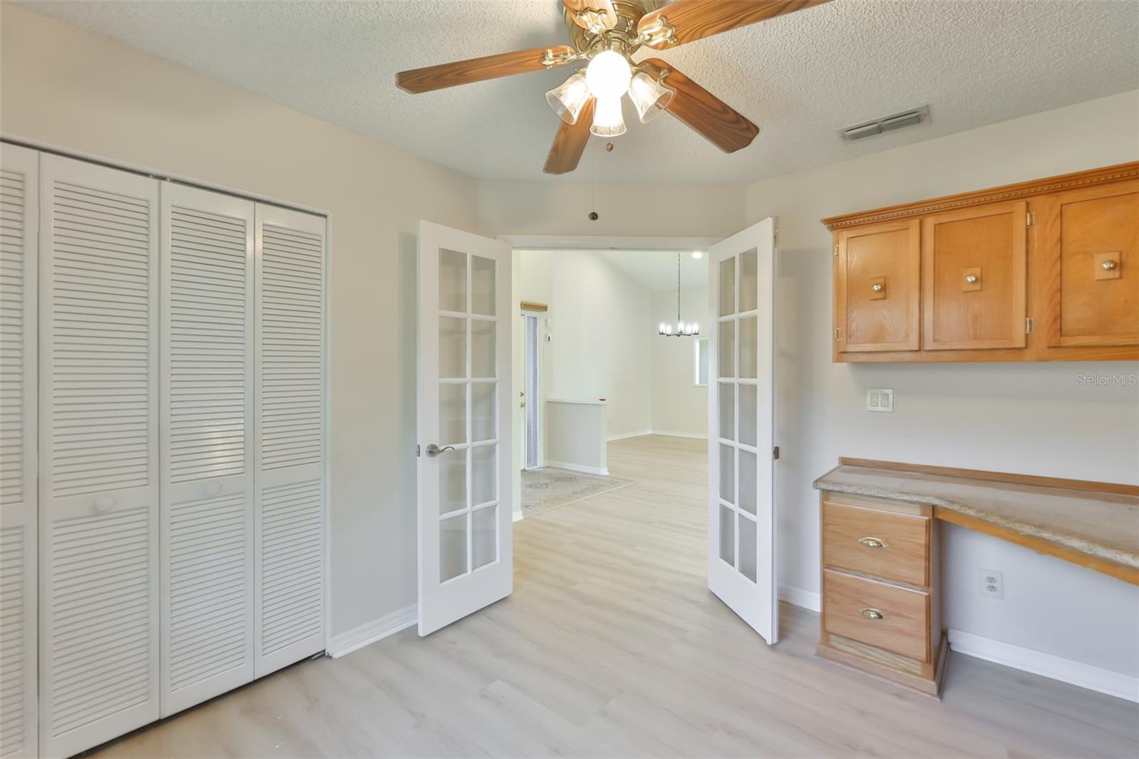 Bedroom 3 with French doors, built-in cabinets, desk, window treatment and Murphy Bed looking to Great Room