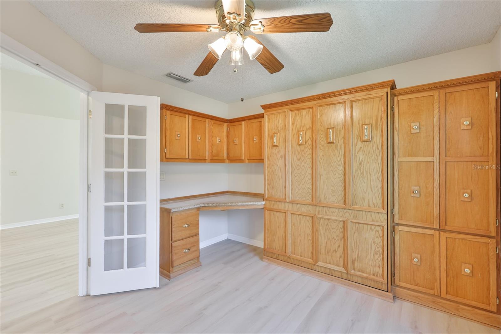 Bedroom 3 with built-in desk, French doors, Murphy Bed and cabinets.