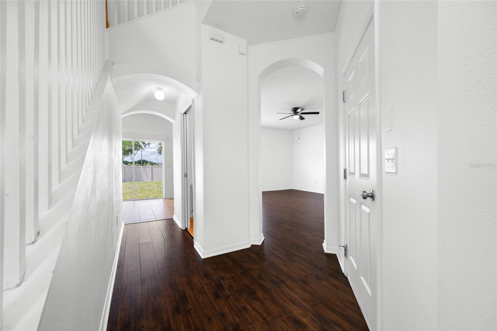 View of Hallway to Guest Half Bath to Sliding Glass Door and Door to Garage and Family Room