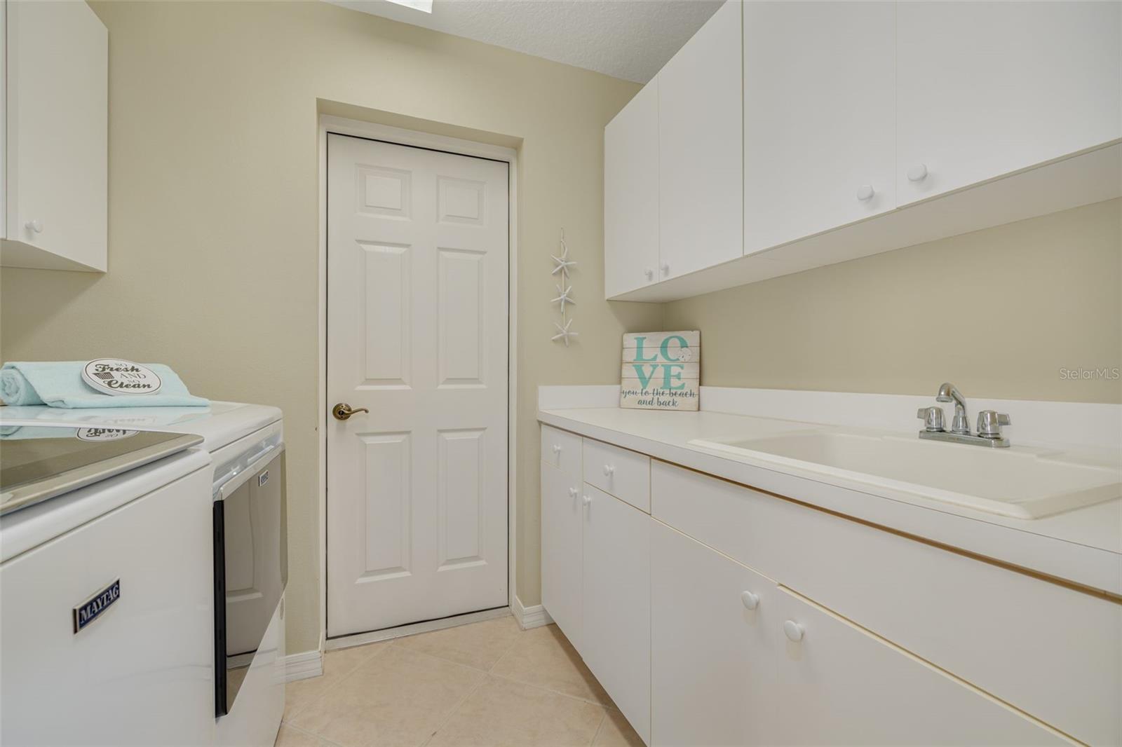 Inside laundry, with newer washer and dryer, plus a sink and plenty of cabinets!