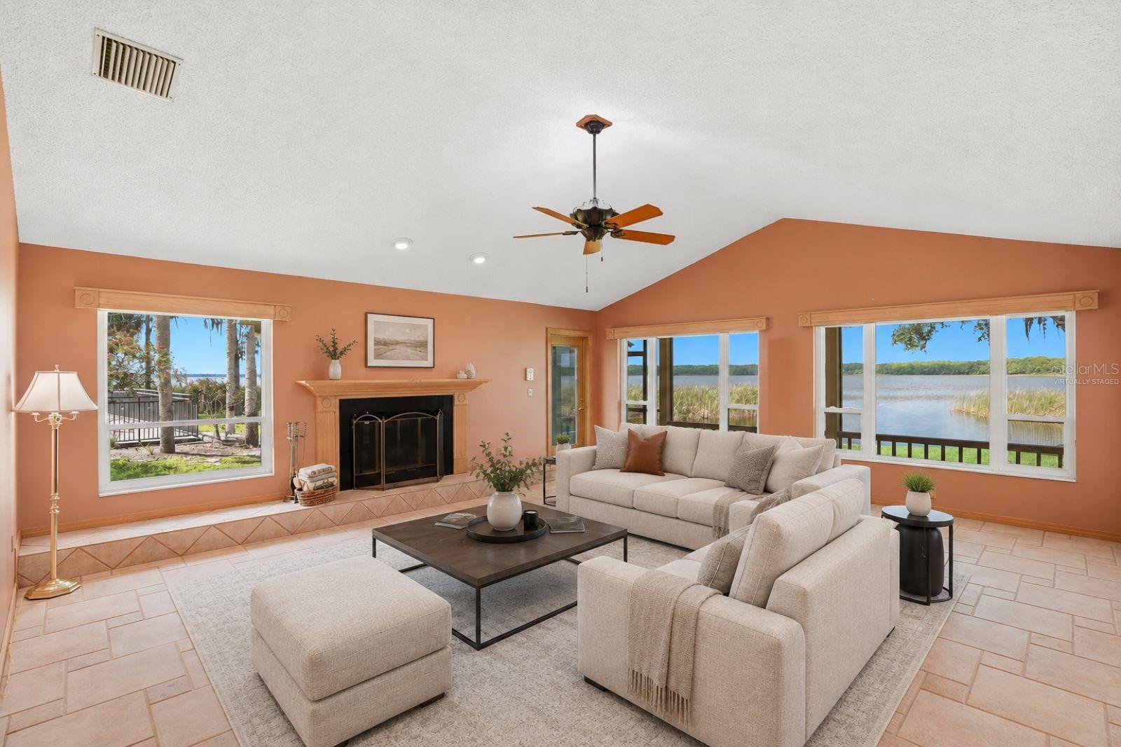 Open Family Room with woodburning fireplace andexpansive views of LakeTarpon and hurricane impactrated windows and Frenchdoors to the enclosed pool..Seamless flow to the kitchen,breakfast area, 3rd bath andpool area -virtually staged