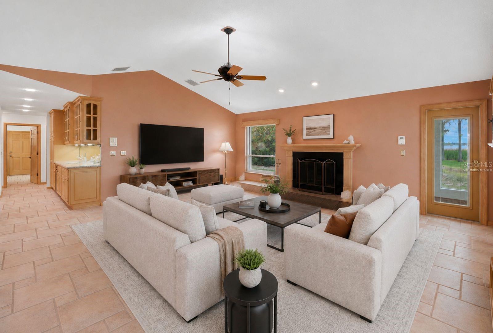 Open Family Room with woodburning fireplace andexpansive views of LakeTarpon and hurricane impactrated windows and Frenchdoors to the enclosed pool..Seamless flow to the kitchen,breakfast area, 3rd bath andpool area -virtually staged