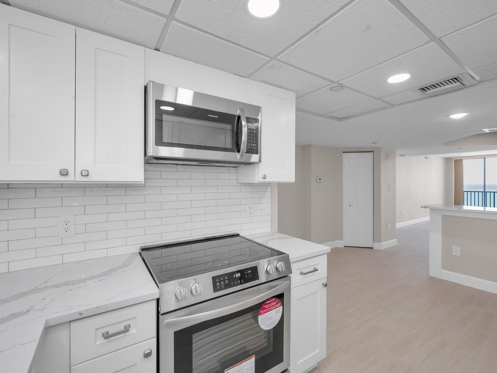 Open Light & Bright Cucina with Quartz surfaces, Shaker Cabinetry, backsplash, recessed lighting equipped with Brand New stainless appliances.