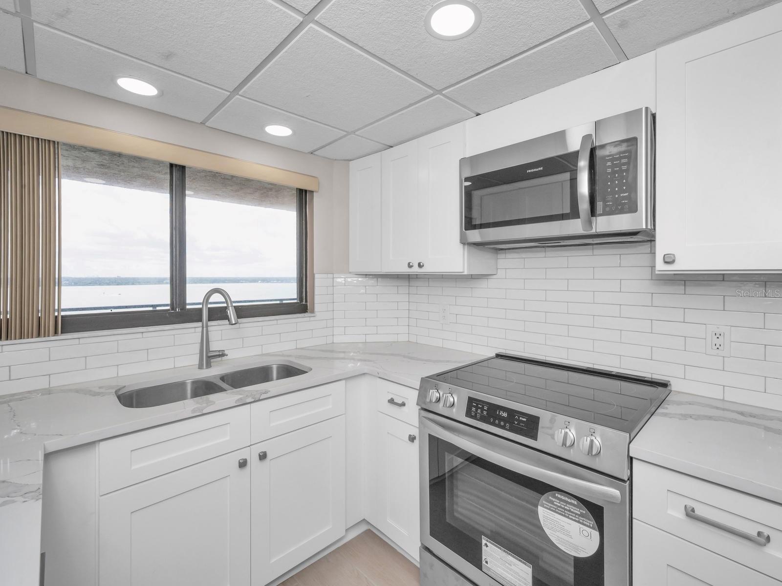 Open Light & Bright Cucina with Quartz surfaces, Shaker Cabinetry, backsplash, recessed lighting equipped with Brand New stainless appliances. Cool Lighted Intracoastal Views!