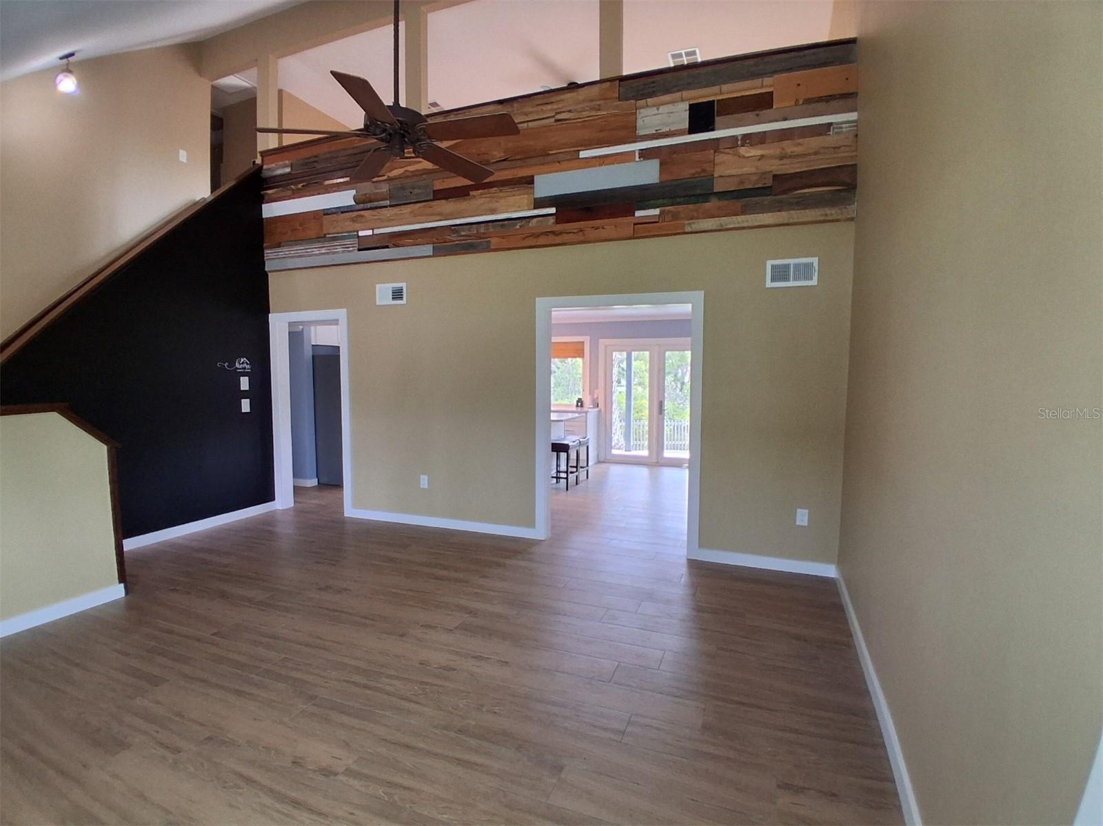 Living room flows seamlessly into the dining area. Check out the creative use of wood planks on the loft wall!