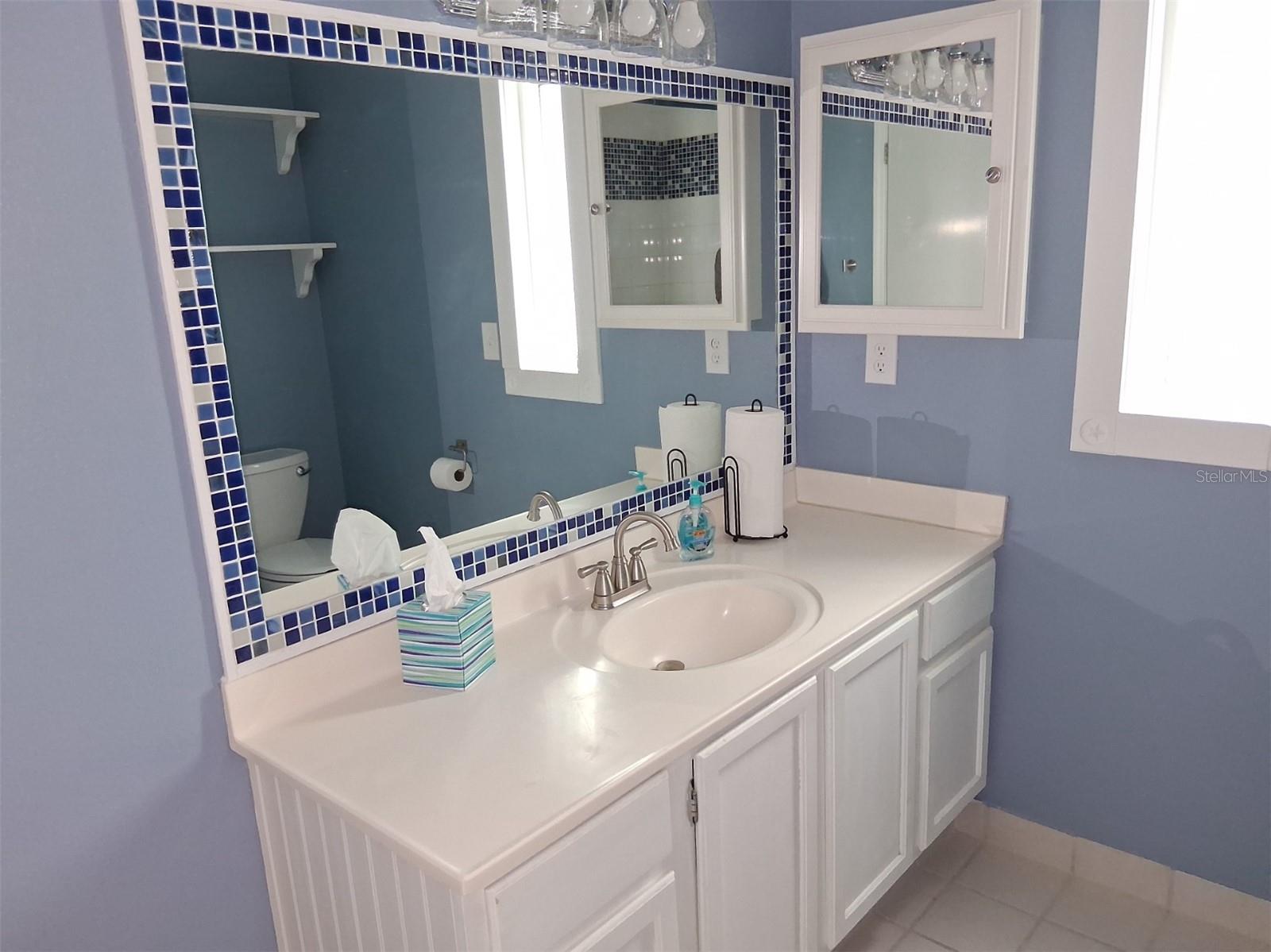Upstairs vanity - love the tile trim and stylish shelving over the commode!