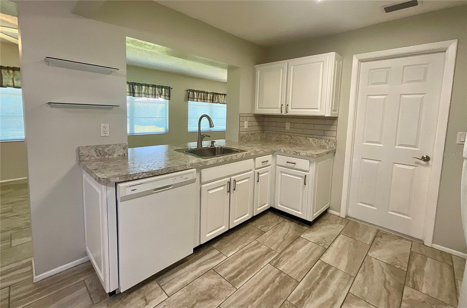 Kichen sink area opening to family room door to garage