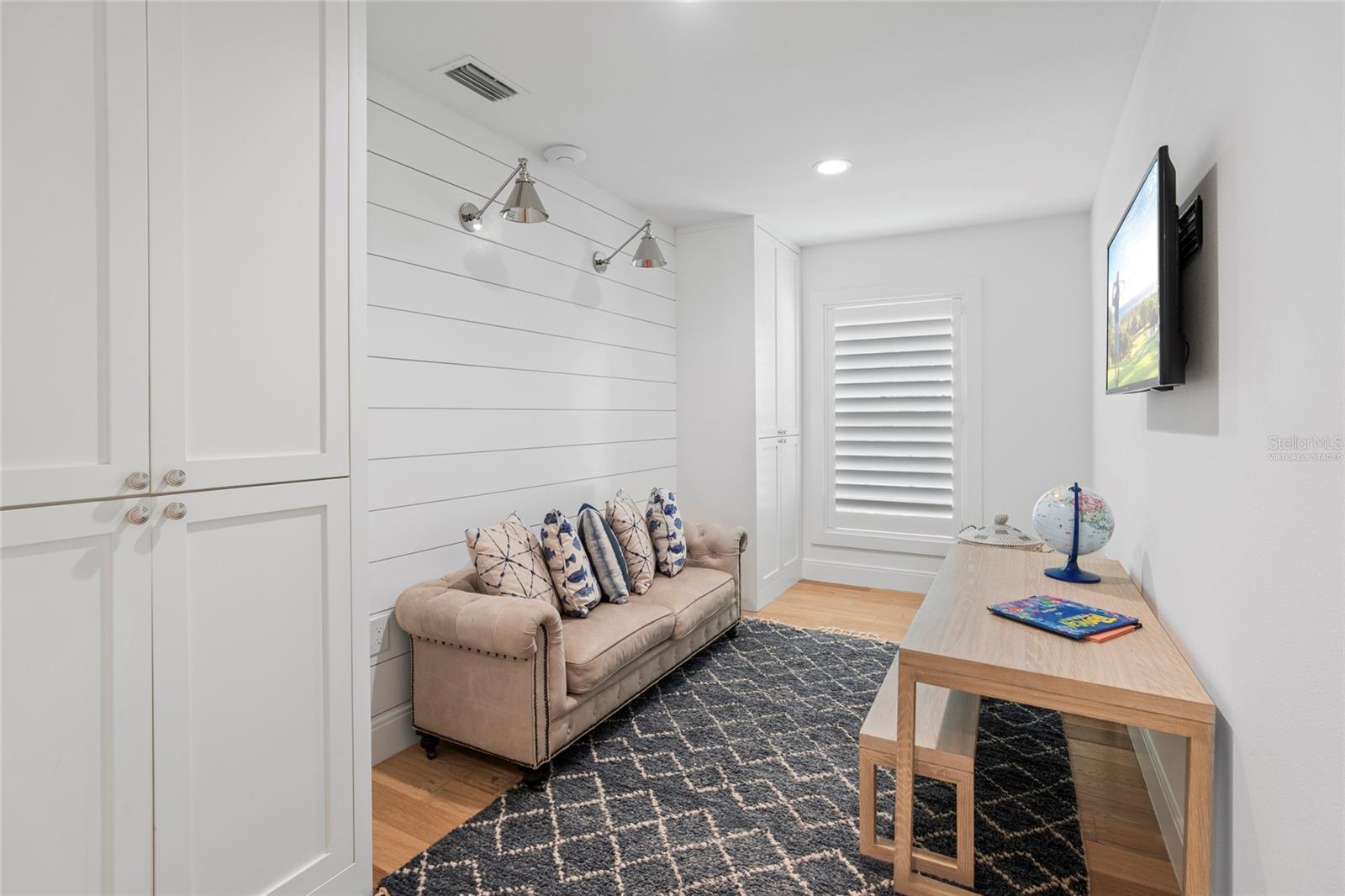 Den/office w/ shell stone tile flooring, custom cabinetry, upscale sconce & recess lighting, virtually staged