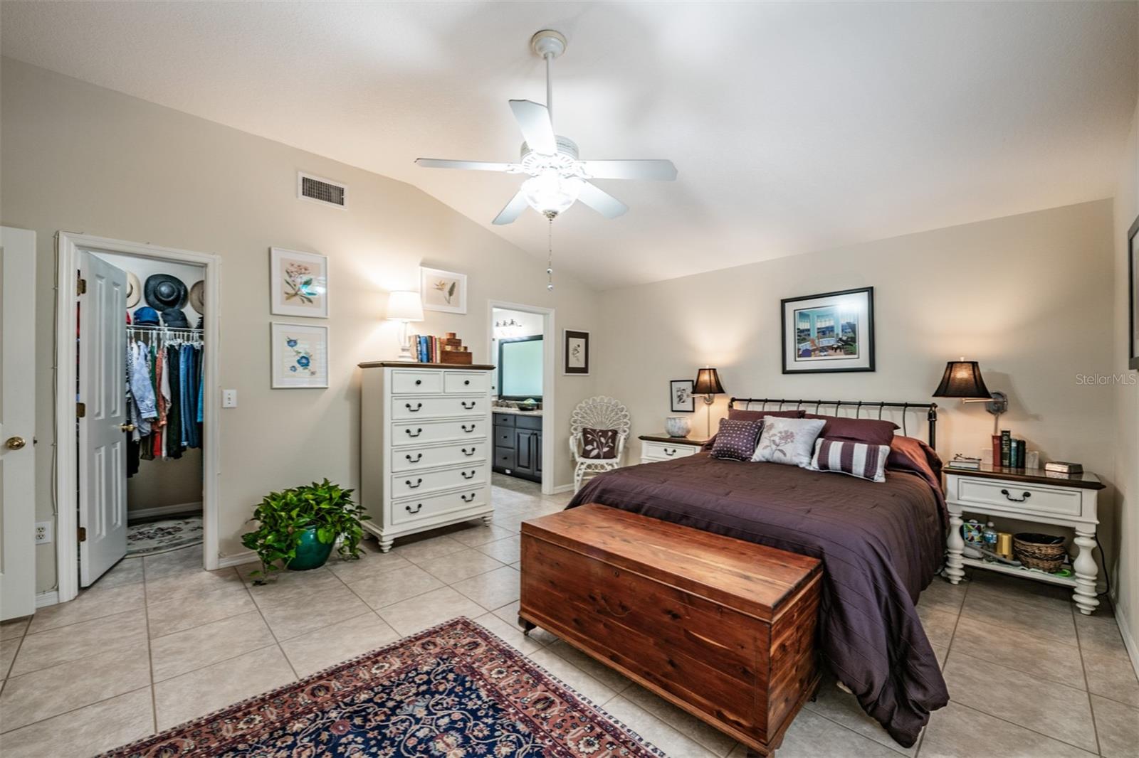 Master Bedroom with Plantation Shutters, Two Closets, Tile Flooring and a ceiling fan with a light fixture.