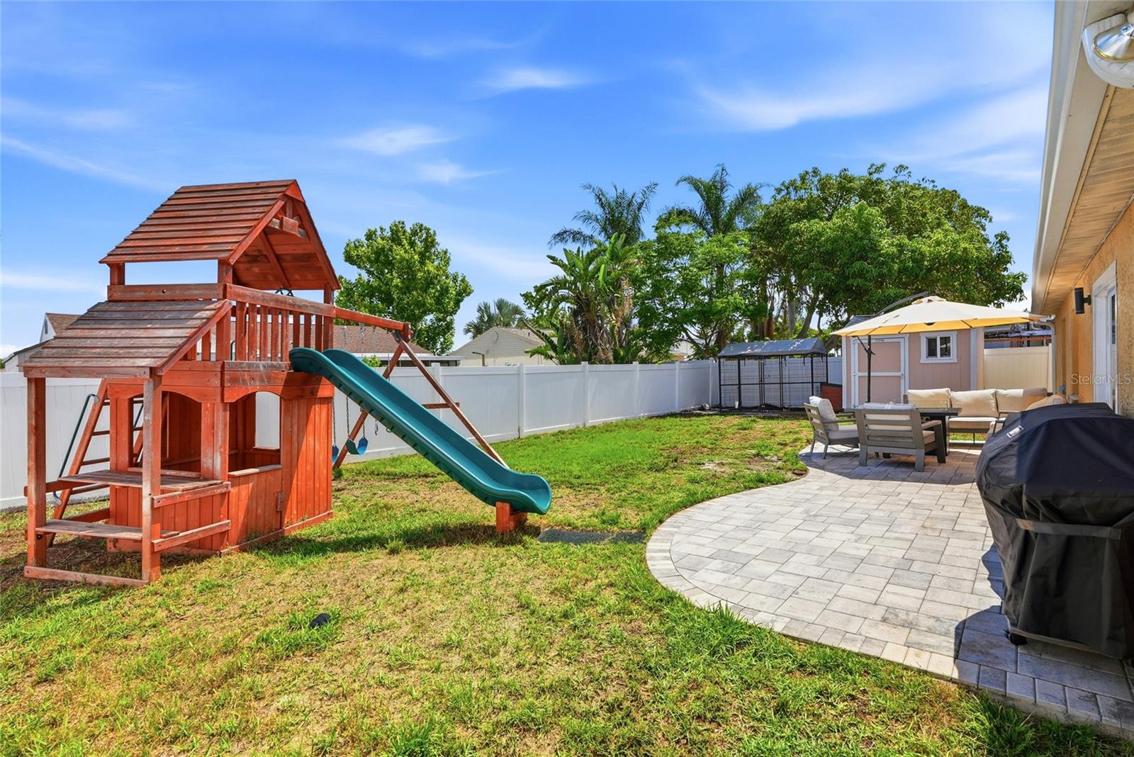 Your fully fenced backyard complete with paver patio, shed and playground!