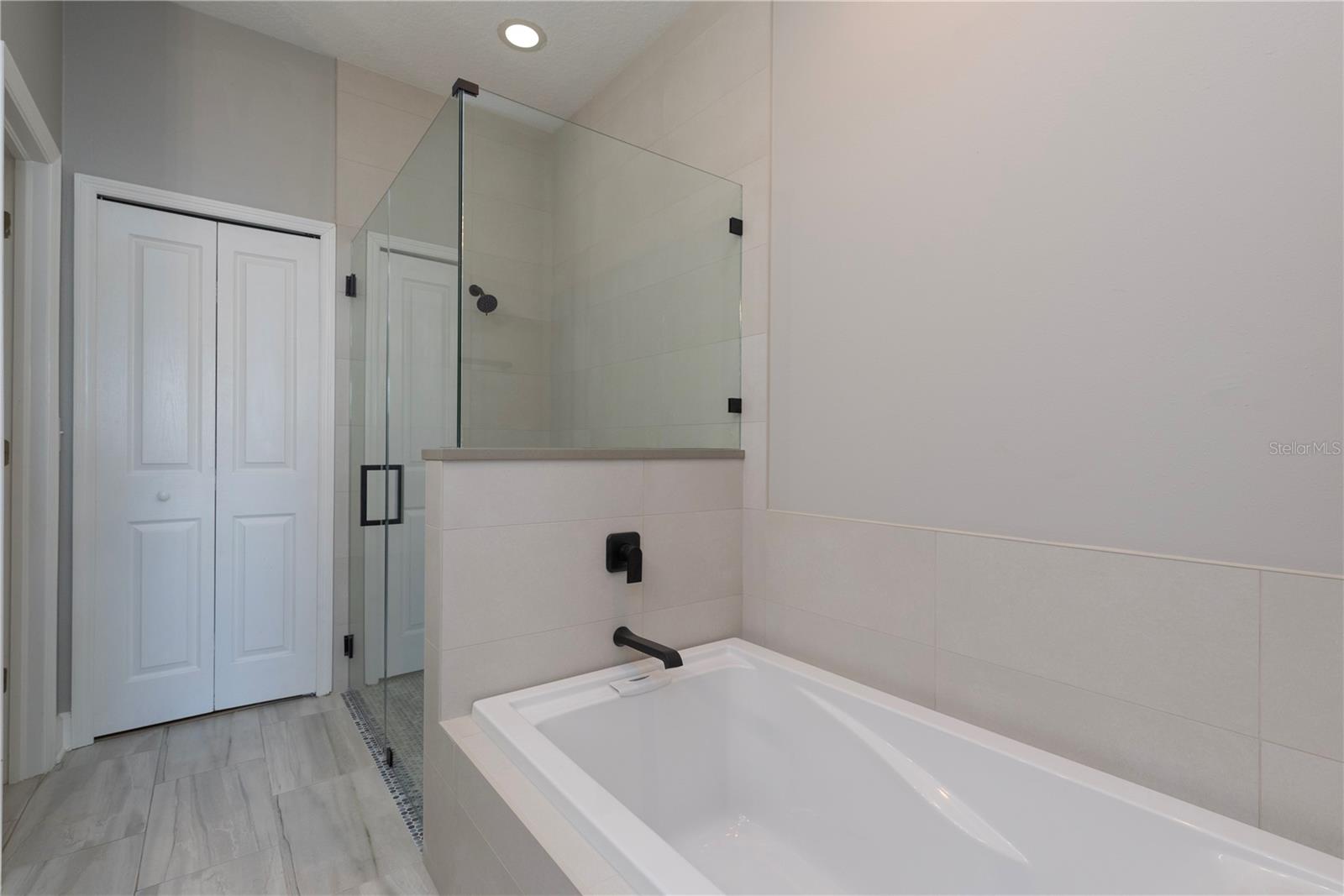 Brimary bathroom with garden tub, walk-in shower, and walk-in closet with built-in shelving and closet system.
