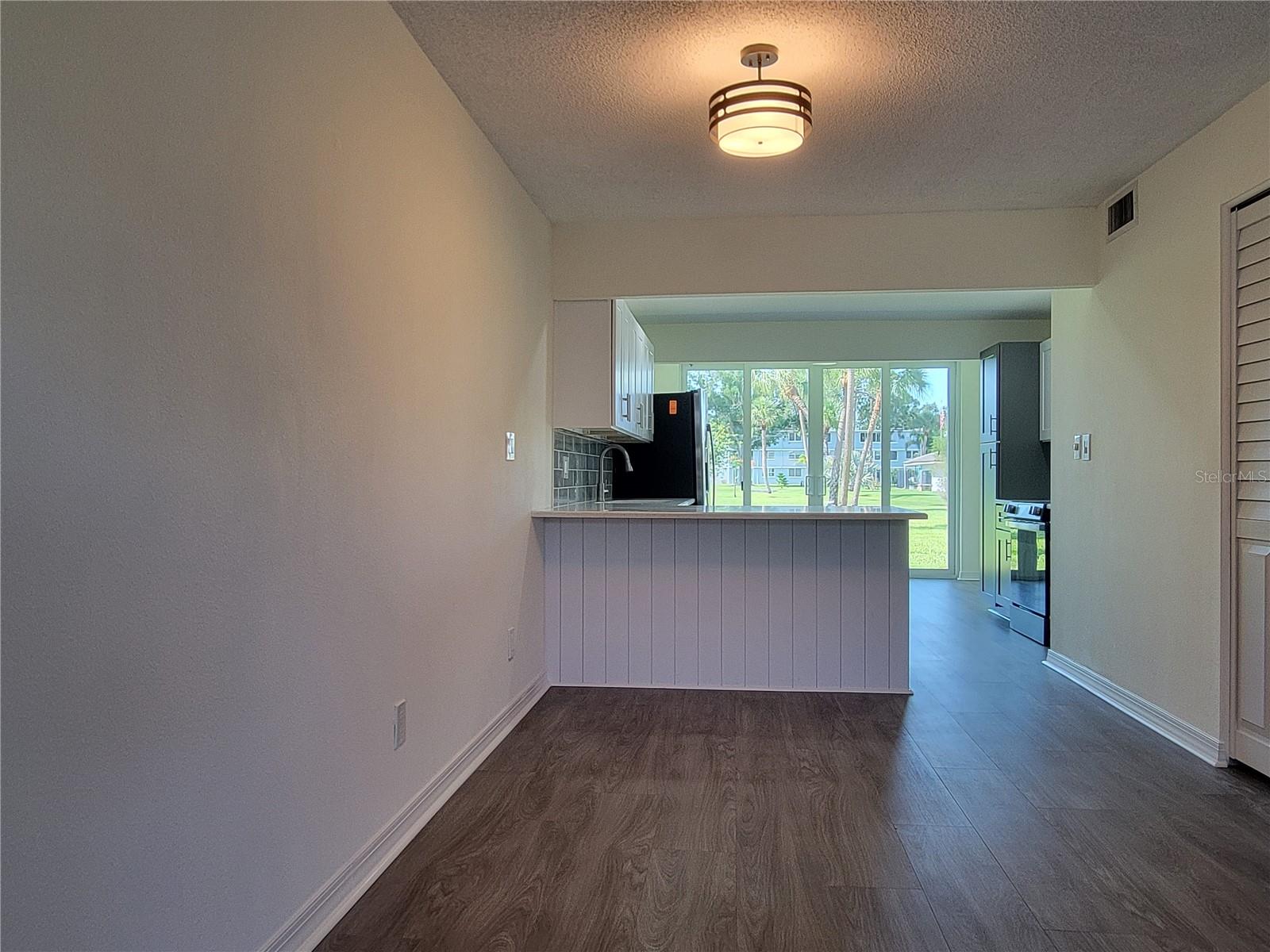 Dining area in foreground with breakfast bar, kitchen and florida room overlooking the clubhouse.