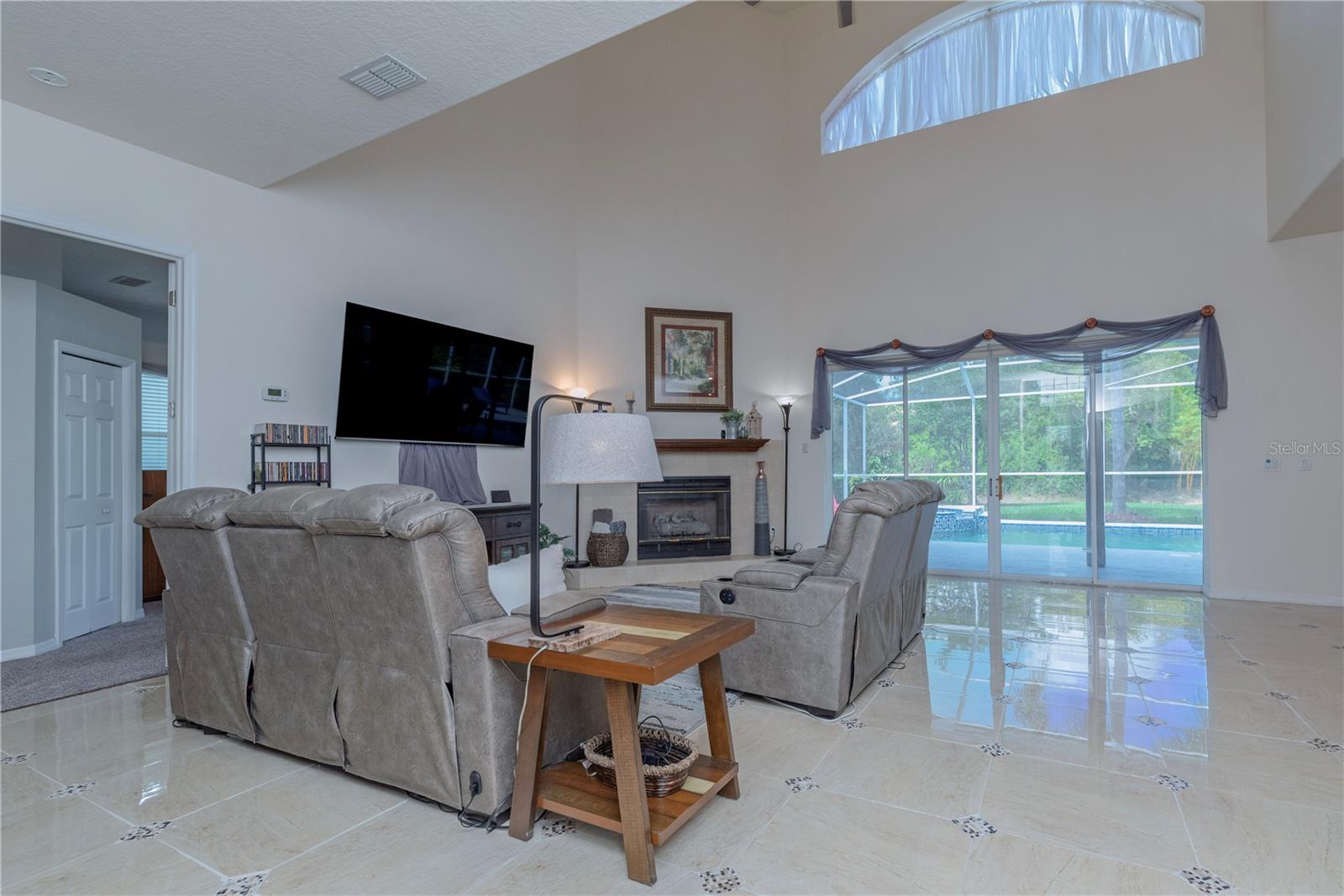 Spacious living room featuring high ceilings and seamless flow to the pool area.